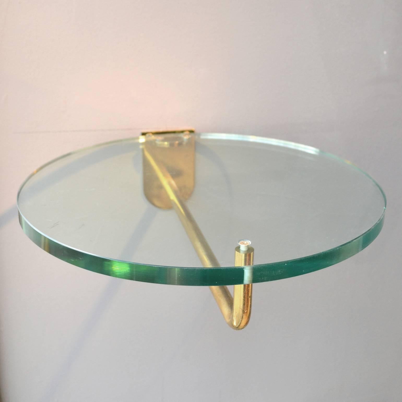 Deux étagères murales:: guéridons ou tables d'appoint rondes en verre sur des cadres en laiton avec un verre de 15 mm d'épaisseur. 
Parfaites comme tables d'appoint (de lit) pour les petits espaces ou comme supports pour les sculptures.