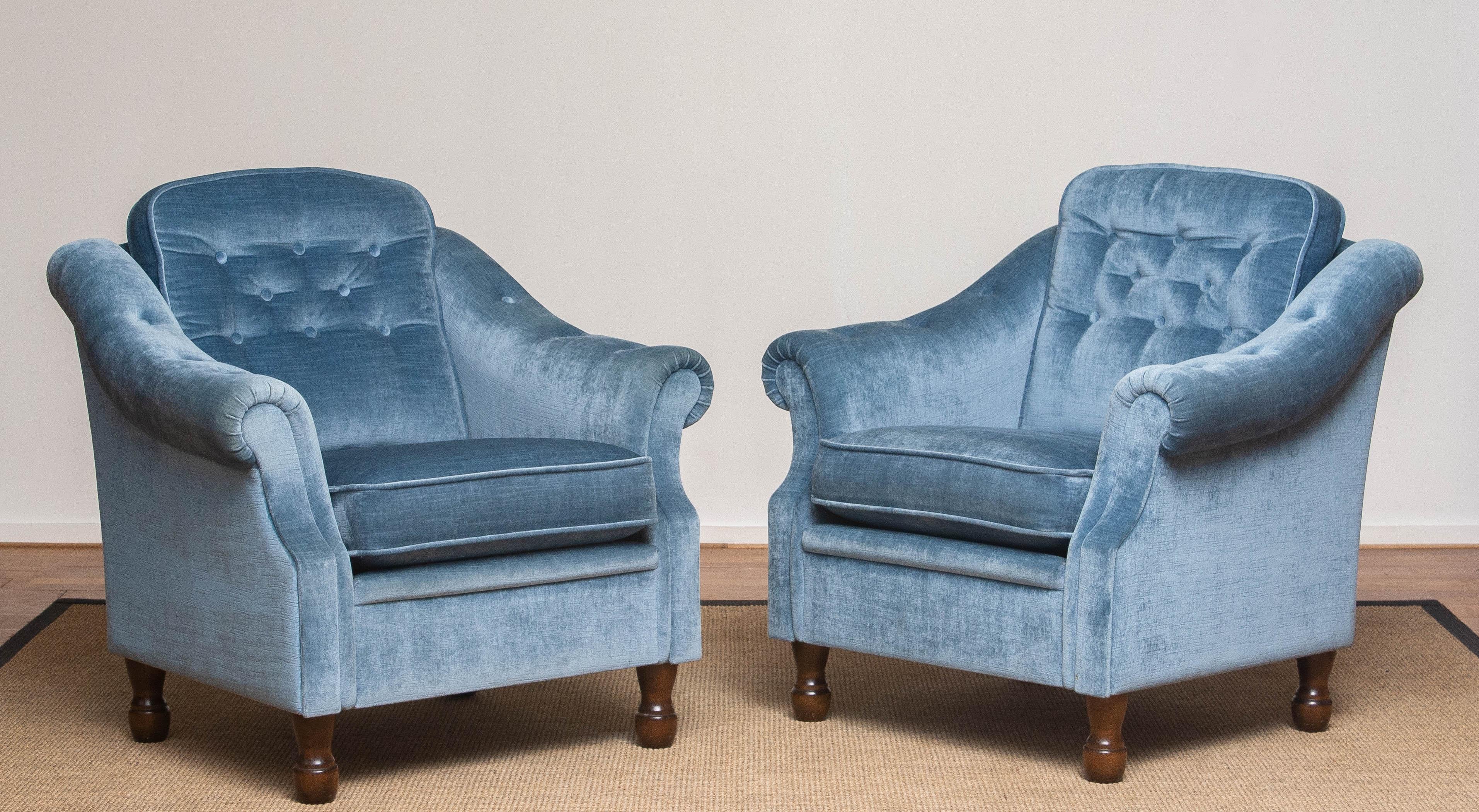 Set of two beautiful and extremely comfortable Swedish Hollywood Regency lounge chairs upholstered with ice blue velvet by Broderna Andersson. The seat and backrest cushion are loose. Backrest and armrests are padded. Both chairs are in very good