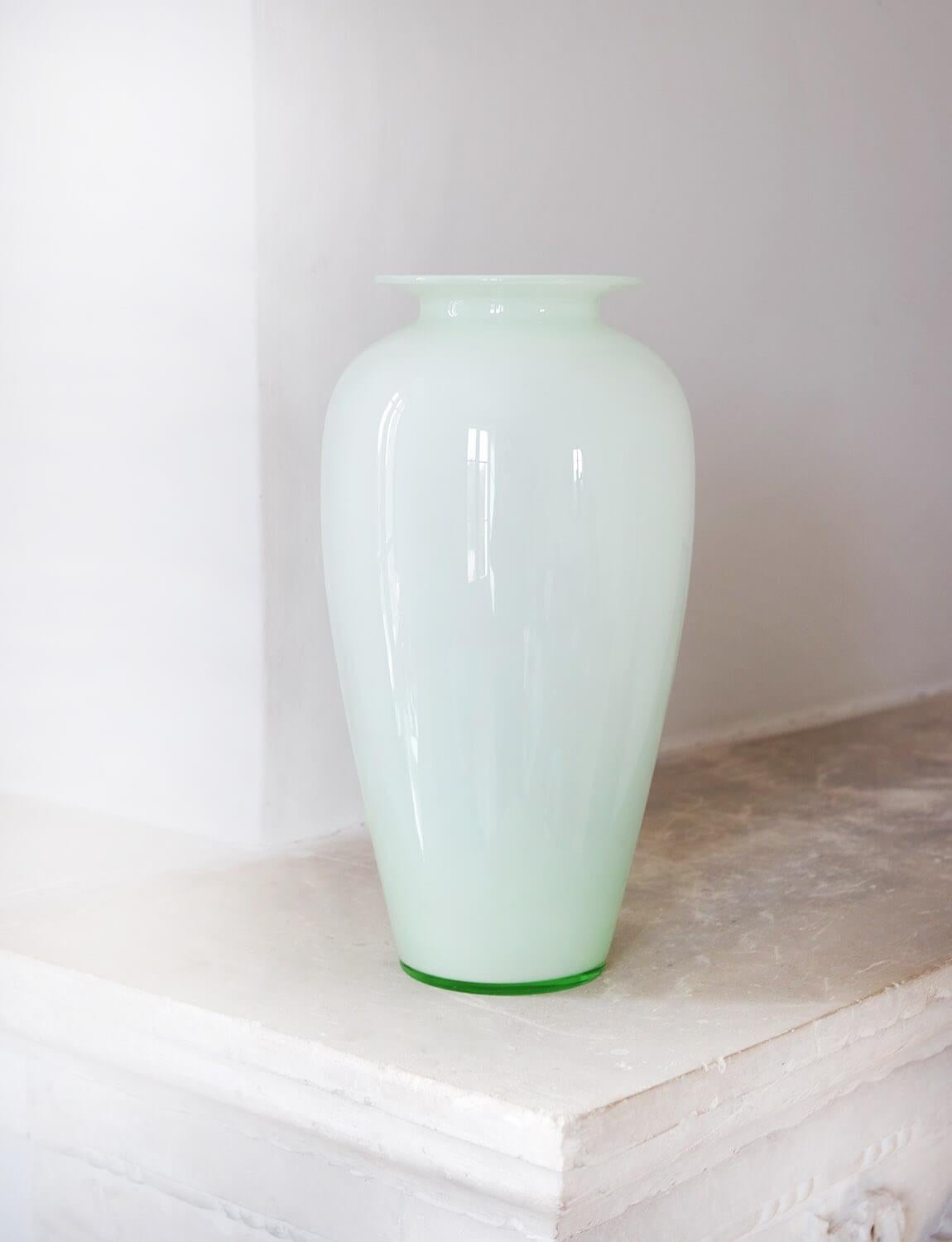 A tall opaque Murano Glass vase in pale green. The vase has a transparent green glass base. This style of vase echoes that of Venini but we have no evidence that this is definitely a Venini piece.  It is nevertheless very elegant. In very good