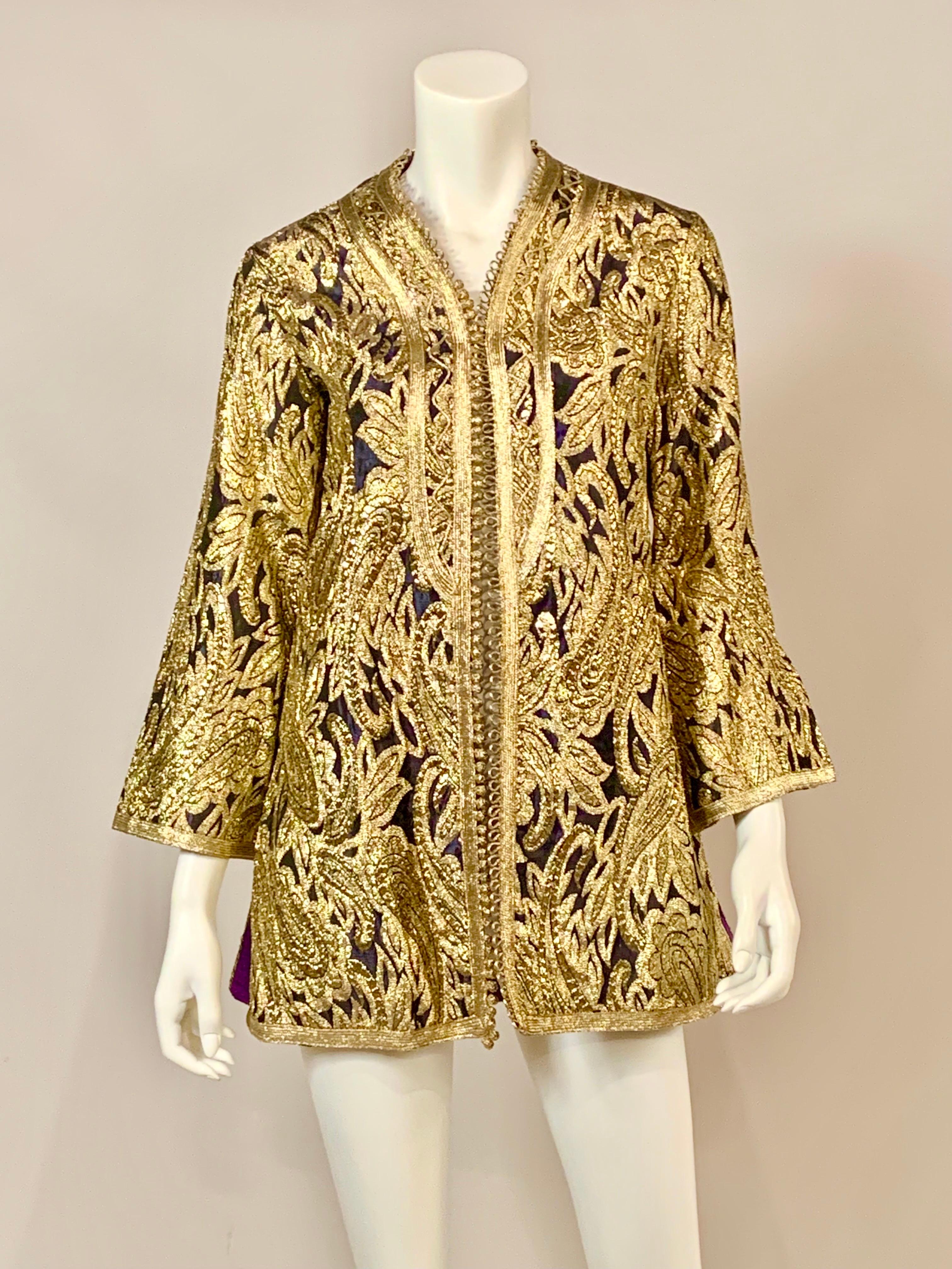 Made in Morocco exclusively for Paraphernalia in the 1970's this jacket is stunning. A deep purple, almost black background is woven with bright gold designs.  There are gold buttons and loops at the center front and on the side openings as well. 