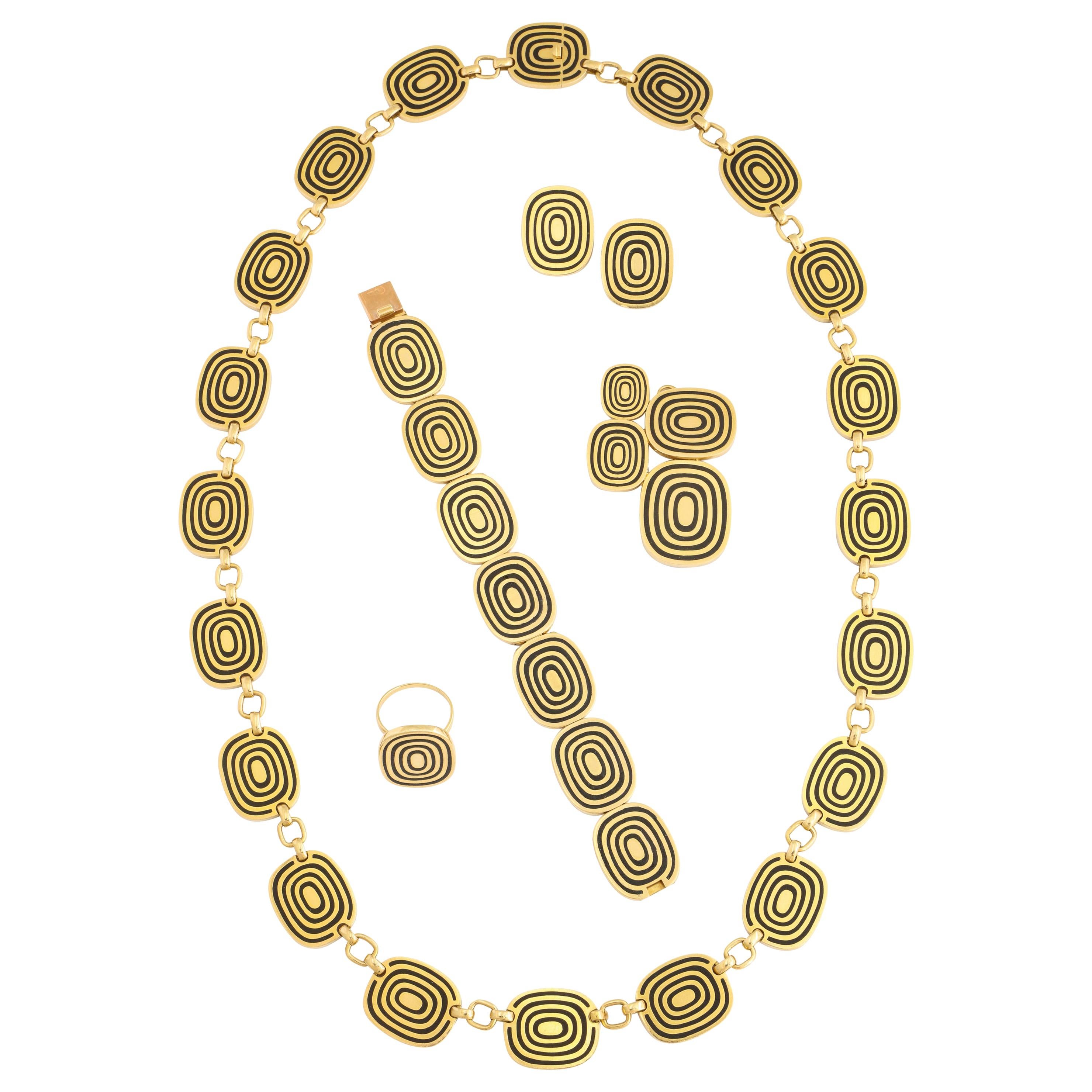 A superb and extremely stylish 1970s 5 piece jewelry suite by Patek Phillippe of 18K gold and recessed black enamel including necklace, bracelet, ear clips, ring, and brooch/pendant. Total weight 315 grams. Disks measure 3/4 inch x 1 inch. Necklace