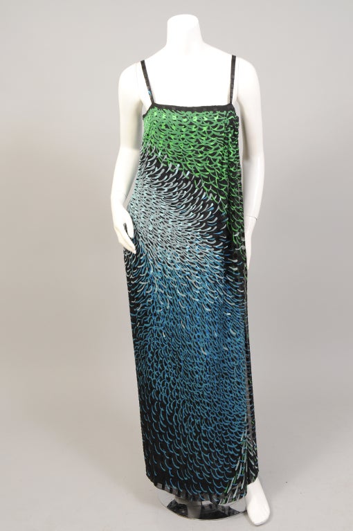A spectacular print is used for this silk chiffon faux wrap style evening dress and oversized shawl from Pauline Trigere circa 1970. The colors range from palest blue to emerald green to brilliant turquoise, all on a ribbon weave silk chiffon. The