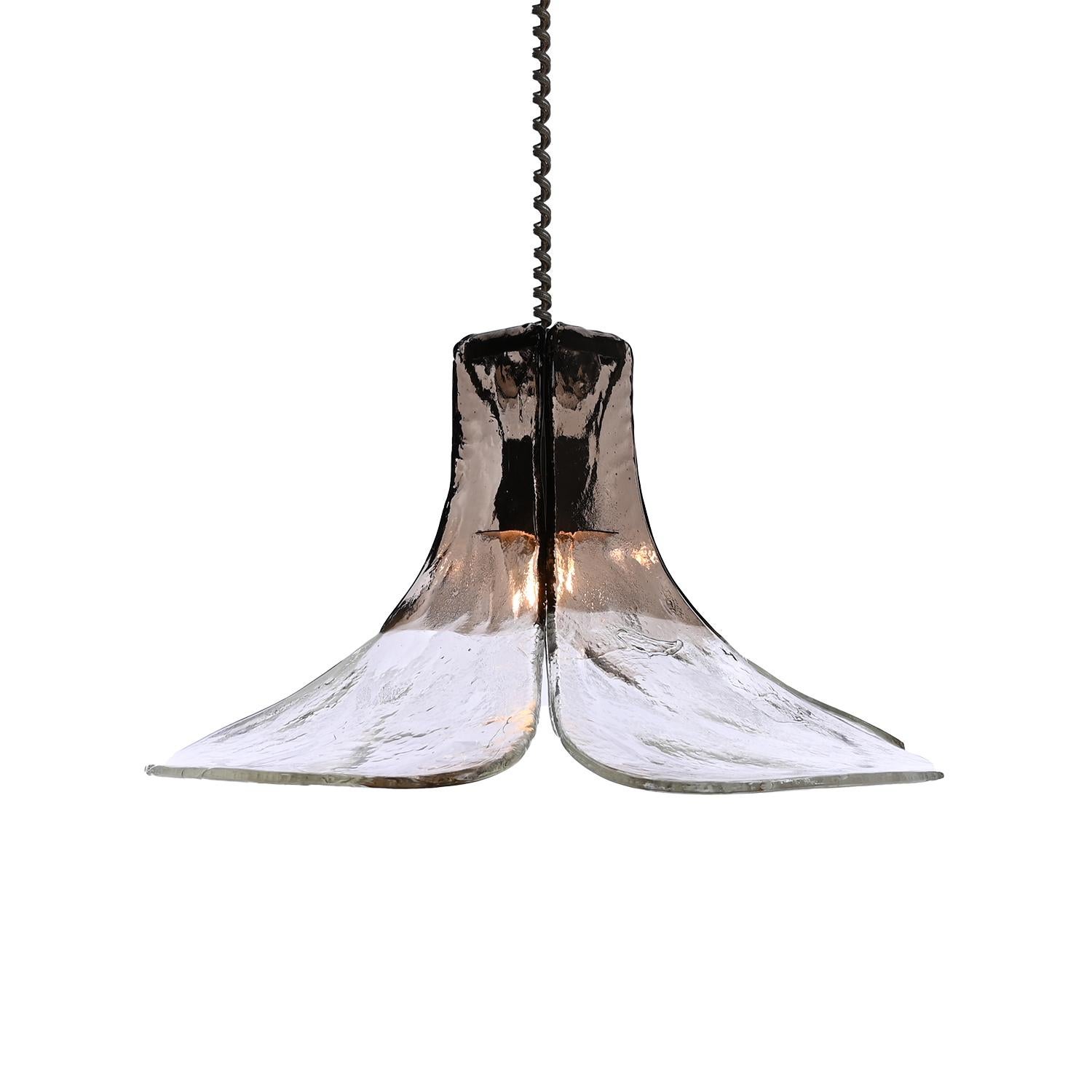 A stylish Mid-Century Modern vintage glass chandelier by Carlo Nason and manufactured by Mazzega, Italy.
4 very thick glass petals shaded from dark tinted glass to clear colored glass, supported by a metal frame. Width of the glass panel starts at