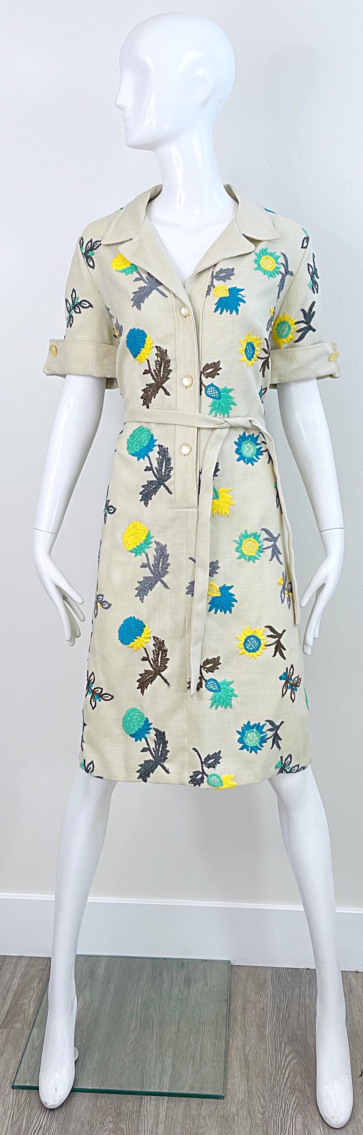 Wonderful early 1970s PETER STEVENS Irish linen khaki embroidered short sleeve shirt dress ! Features embroidered flowers in cobalt blue, turquoise, green, yellow, brown, and grey. Buttons up the front. Tie belt at waist. Very well made, with heavy