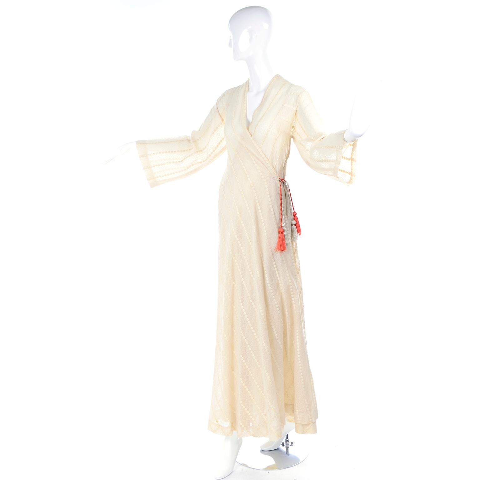 This is a true bohemian style vintage dress from the 1970's in a cream embroidered cotton voile fabric with raised dots.  The dress looks like a hostess gown, but is worn as a day or evening dress and closes with orange and cream tassel ties. Sheer