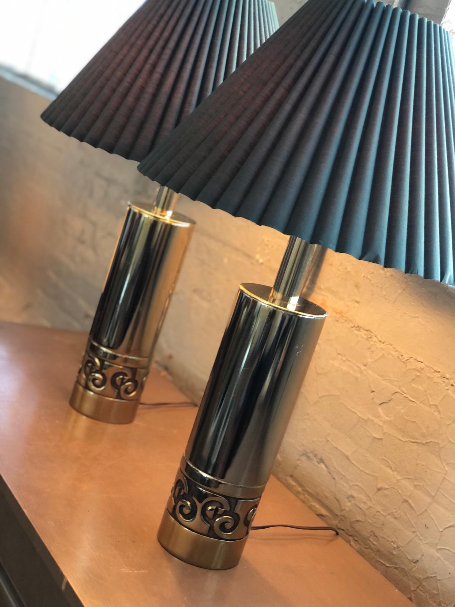 An amazing pair of  vintage Pierre Cardin cylinder brass lamps with a banded relief pattern at the base that nods to the signature PC logo.  

The vintage shades feature a cut box pleats in a deep evergreen hue that compliments the contemporary lamp