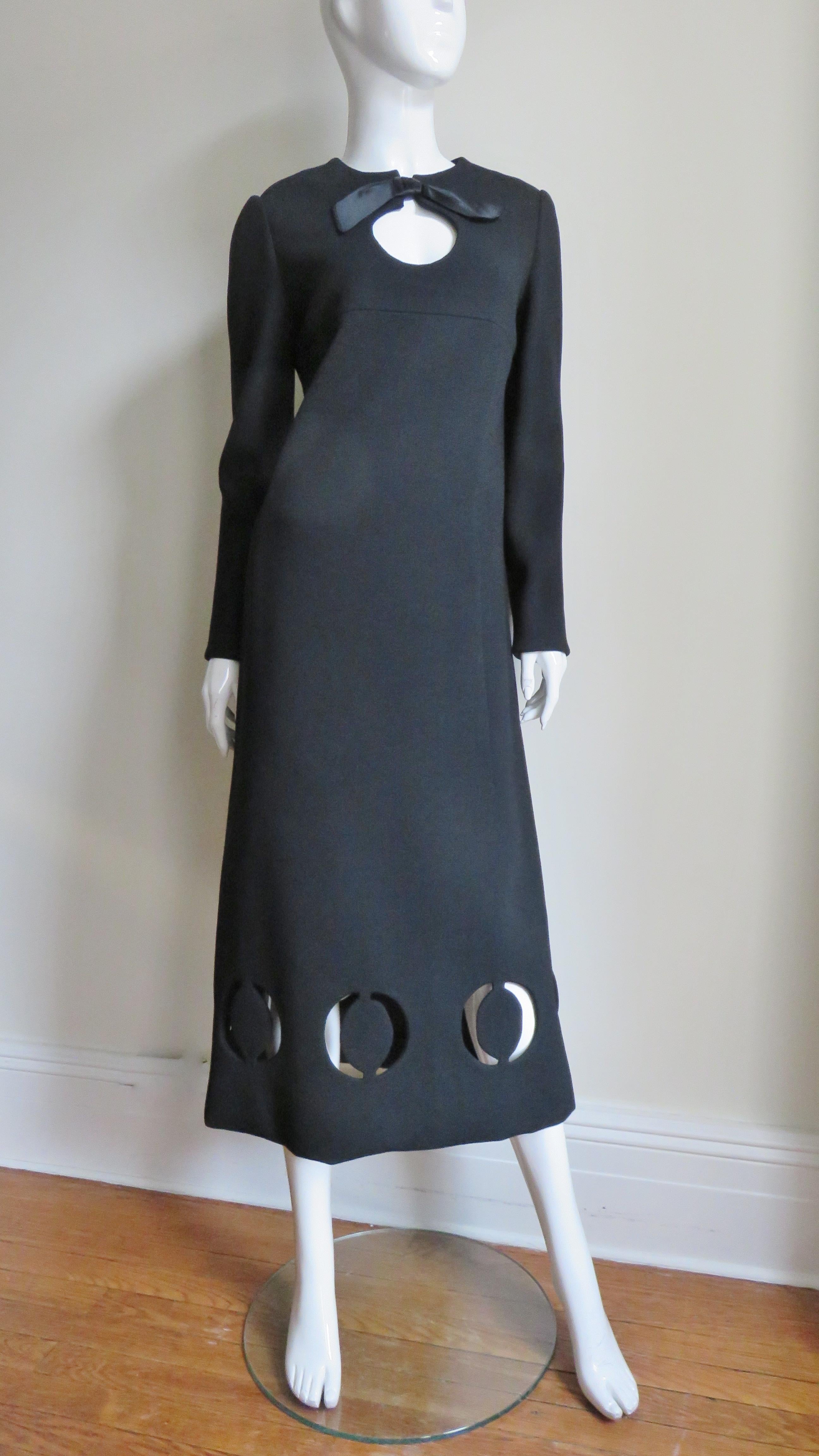 A fabulous black wool midi dress from Pierre Cardin. It has long sleeves, a crew neckline with a silk bow at the top of a front circular cut out. There are front and back yokes and the dress subtly flares towards the hem.  Around the hem
