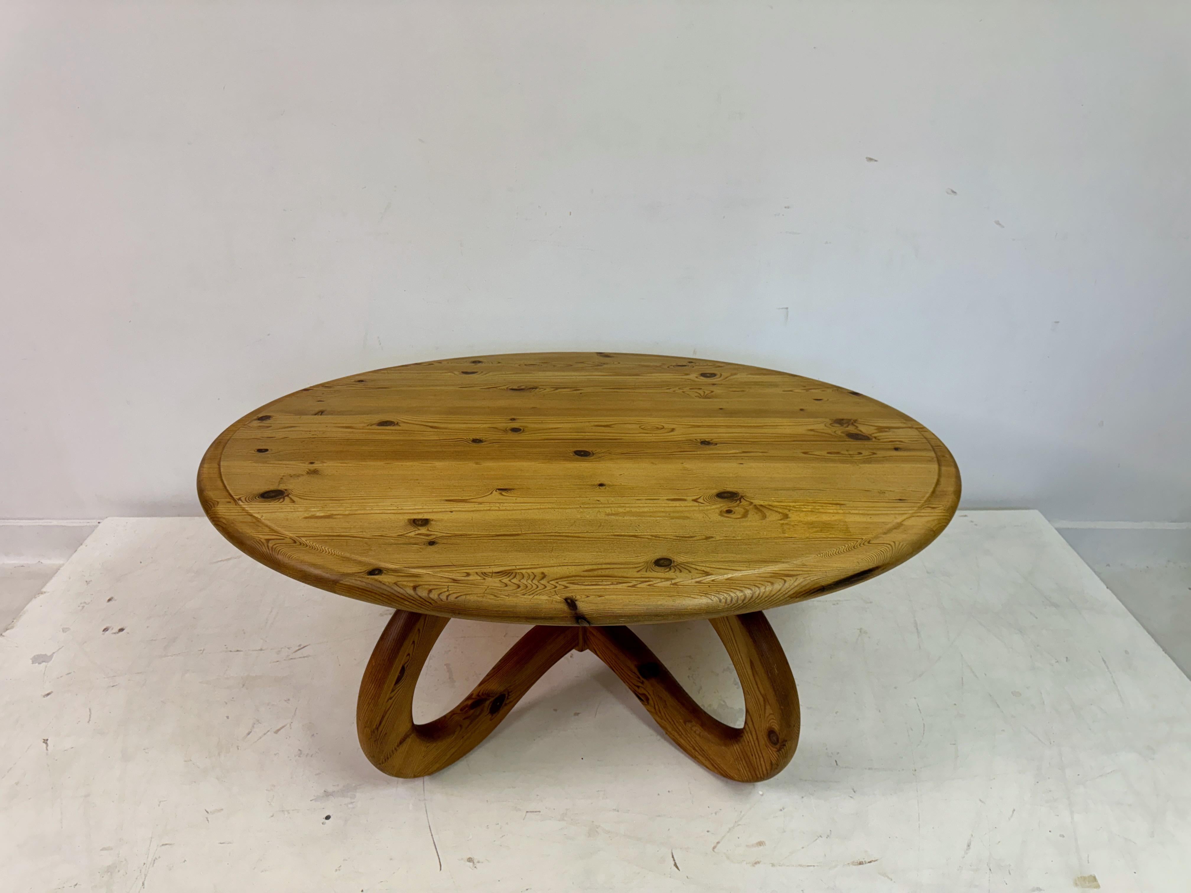 This unique pine coffee table combines rustic charm with modern artistry. Crafted from solid pine, the table features a round top that highlights the natural grain and knots of the wood, giving it a warm and inviting appearance. The surface has a
