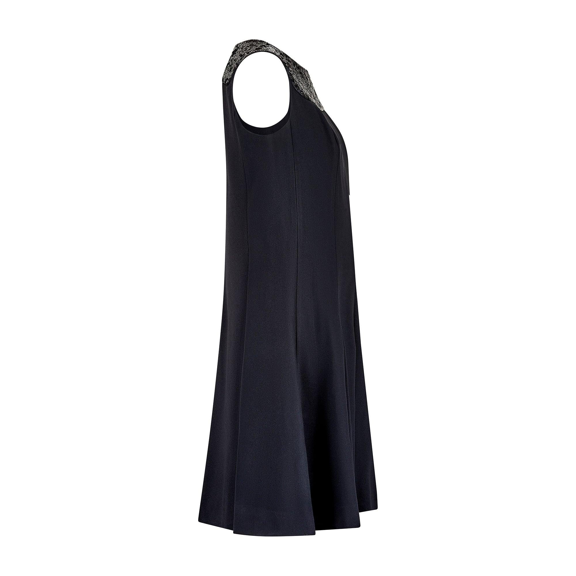 Cette élégante petite robe noire a été conçue par Pisanti au début des années 1970. Taillée dans une silhouette intemporelle, elle est sans manches et présente une large encolure bateau gracieuse. Il est de forme trapèze, avec une jupe légèrement