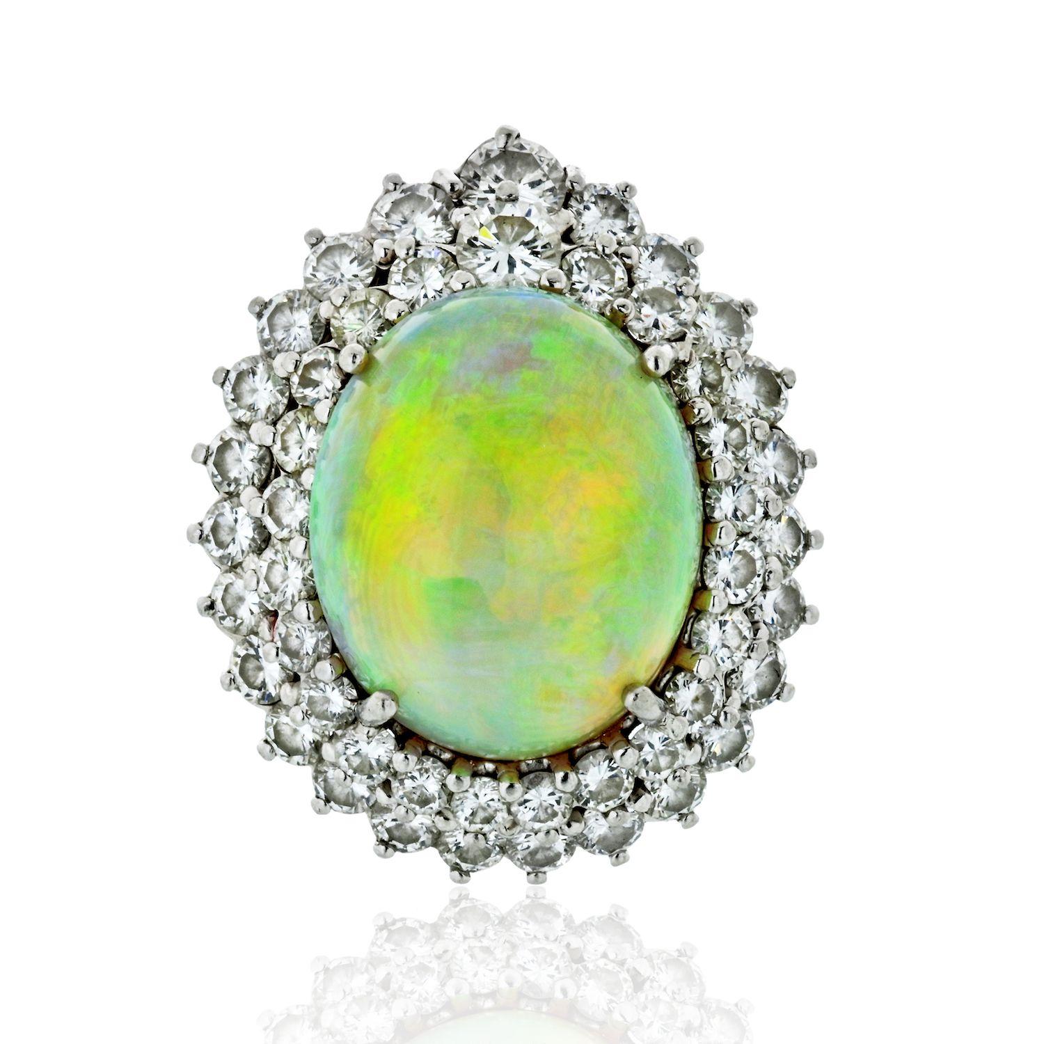 Platinum Opal & Diamond Ring, large opal of rainbow fire, low dome cabochon, 48 round-cut diamonds as double halo, diamonds of H-I color VS-SI clarity, app 4.50 ct tw.
Circa 1970.
Ring size 7.5