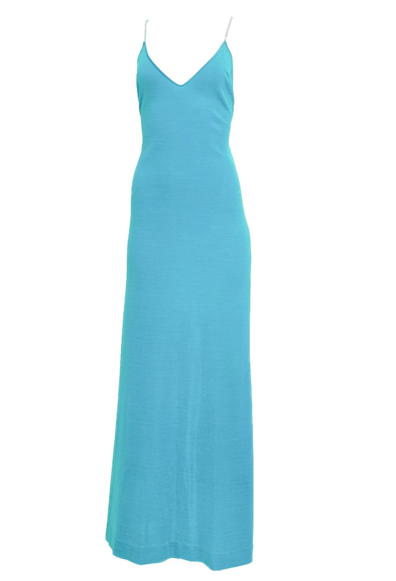Este vestido vintage de punto turquesa de los años 70 destila glamour con sus brillantes detalles de pedrería y su llamativo diseño abierto de espalda cruzada. El vibrante tejido turquesa drapea con elegancia, mientras que la alta abertura en la
