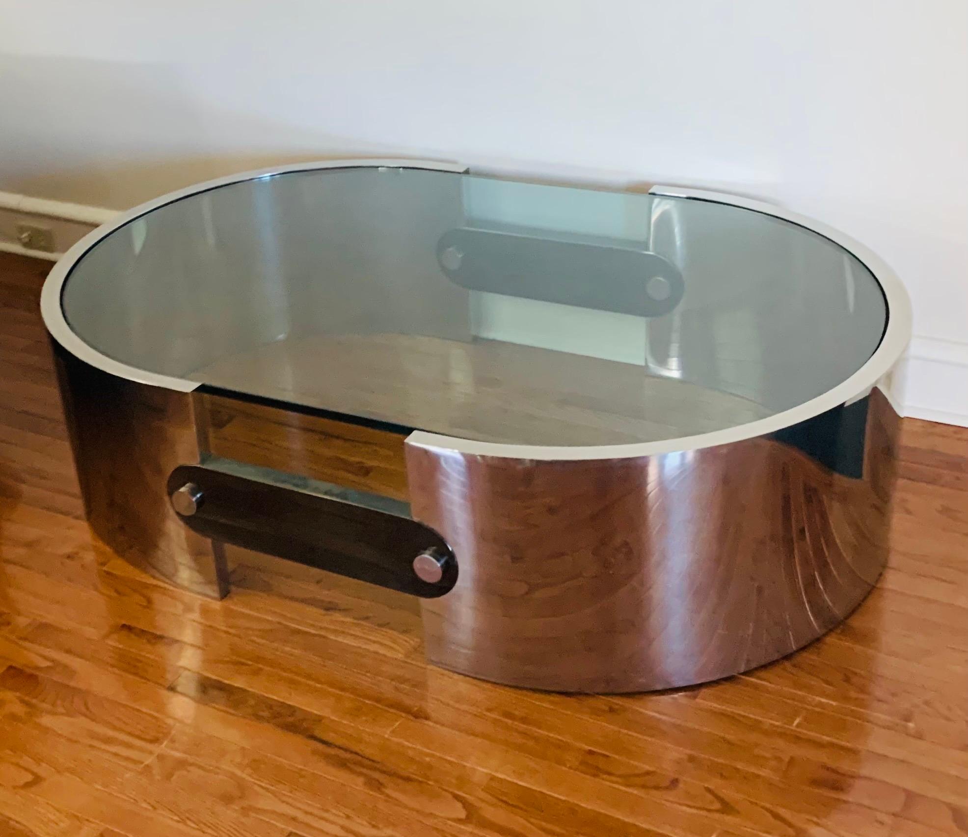 This is a very large, highly-polished stainless steel and glass cocktail table by Ron Seff. It was produced sometime in the 1970s in the USA. The piece was custom made in NYC for its one and only owner.
 
The design features a racetrack-form ring of