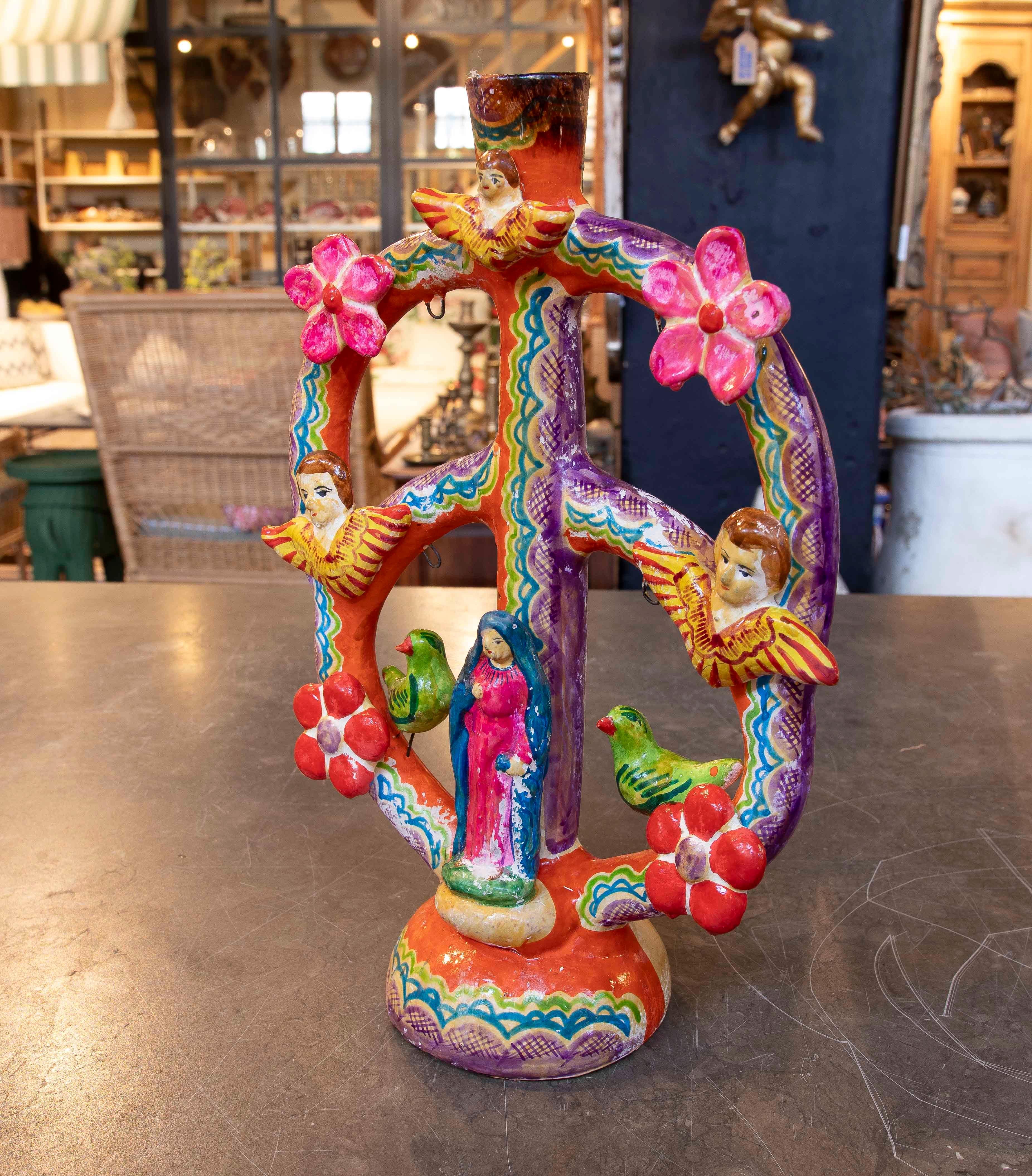 Polychrome ceramic piece known as Tree of Life, representing religious and decorative elements. In the center is the figure of the Virgin Mary, surrounded by winged angels, flowers, and birds, all elaborated with bright colors and hand-painted