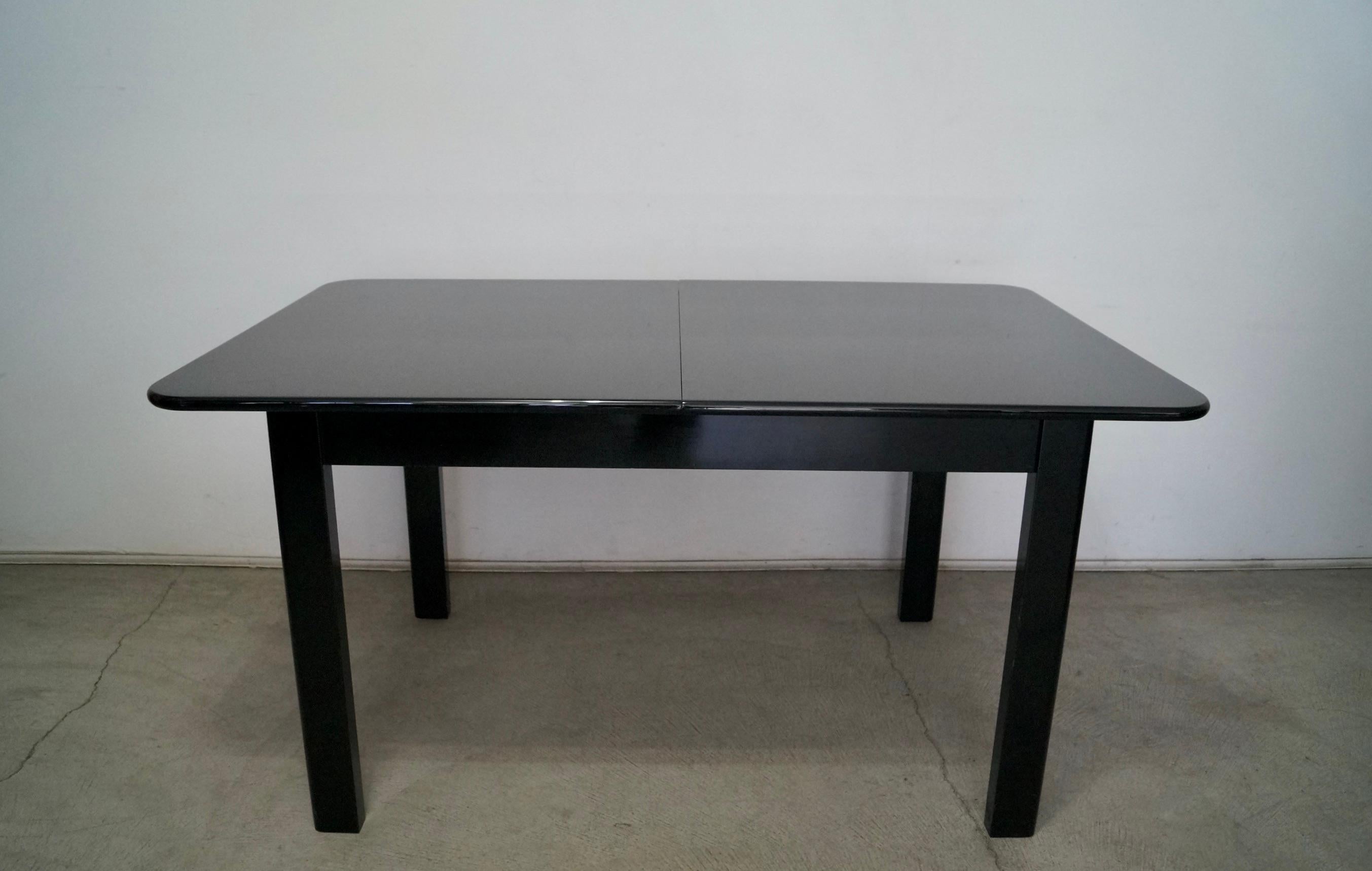 Vintage 1970's Post modern dining table for sale. Manufactured by Montina in the 1970's, and made in Italy. Made of solid wood, and has the original black lacquer in excellent condition. It has a great Hollywood Regency Art Deco design with rounded