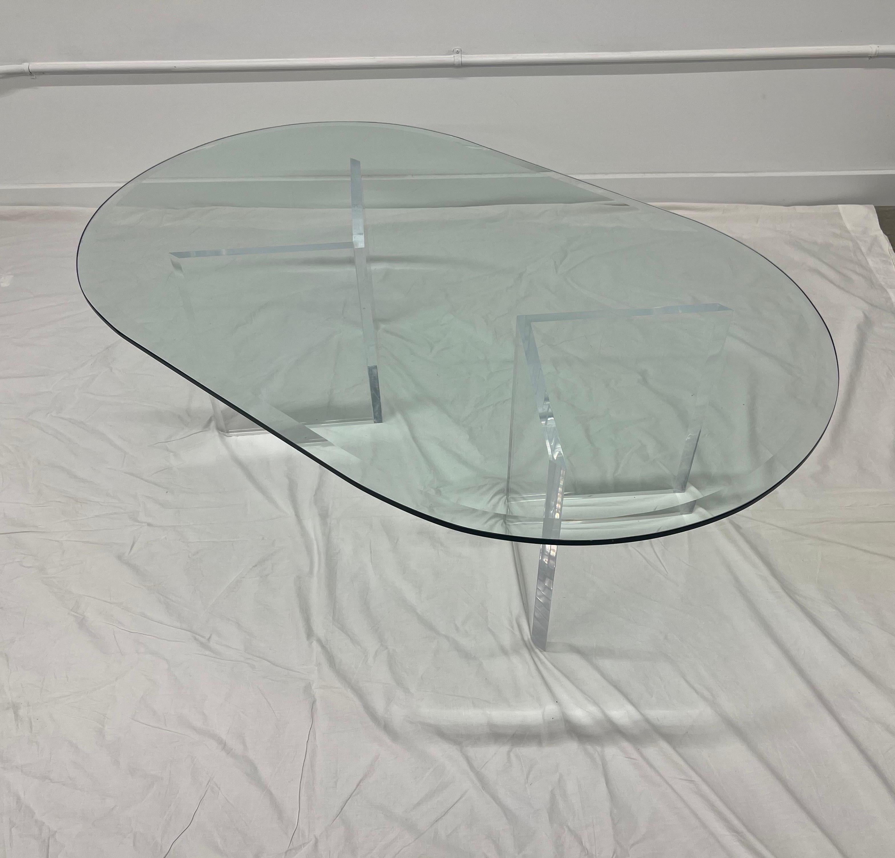 Unique vintage coffee table with two lucite / acrylic “V shaped” bases. A beveled, oval, glass top rests on top. It’s light and airy and you could easily display items within the acrylic.
