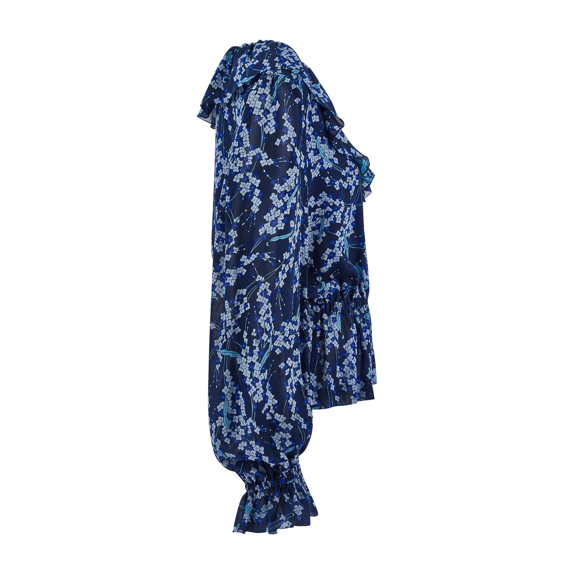 Designed by Emilio Pucci, this ruffled, bohemian blouse is crafted from semi-sheer, pure silk. Showcasing his famous flair for print design; graphic florals and vines in shades of blue are interwoven with Emilio's signature. Tailored to a peplum