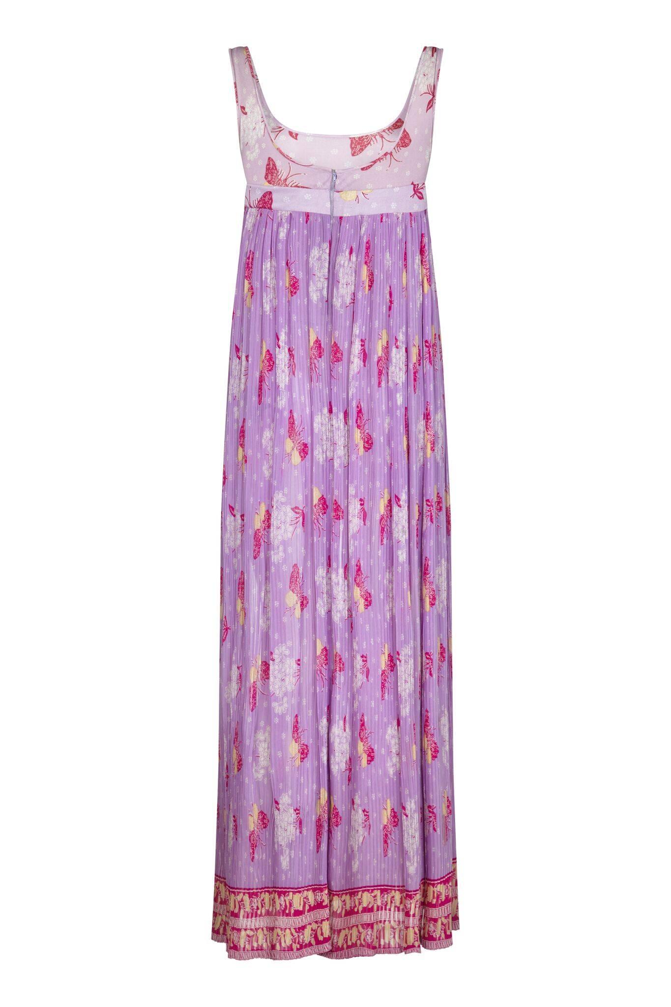 Este bonito vestido púrpura de los años 70 de línea imperio con motivo de mariposas tiene un aire bohemio y veraniego. El vestido de cuerpo entero está compuesto por un fino tejido de rayón para la falda en un tono lila que se suaviza en un tono