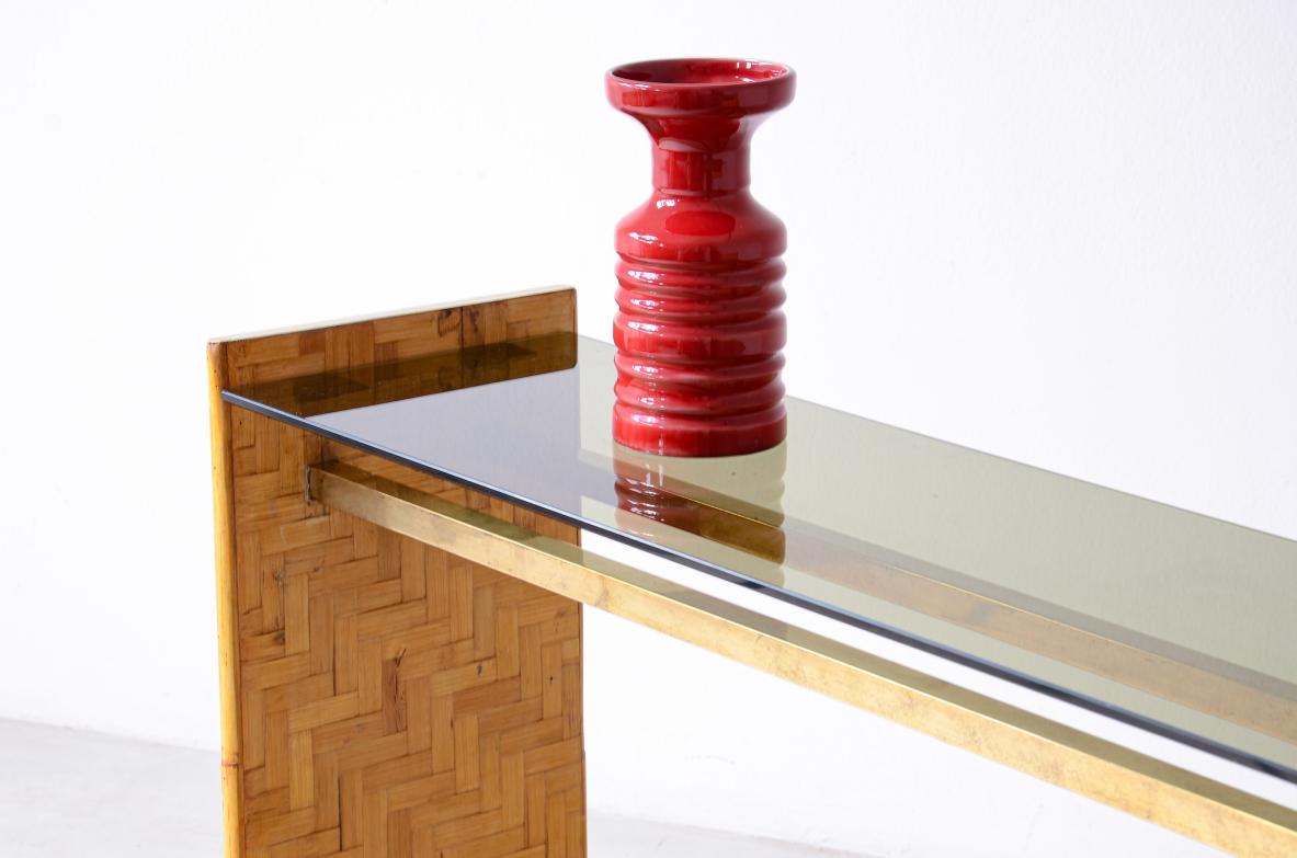 COD-2786
Console with two uprights in wood and raffia with brass tie rods and burnished glass top.  
Italian 1970s manufacture. 