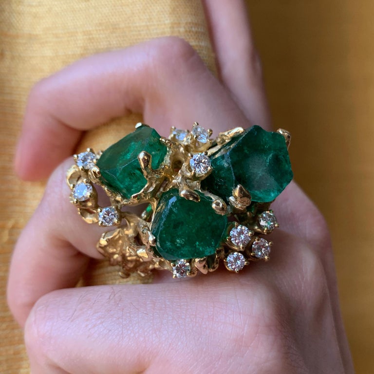 A vintage, one-of-a-kind, highly stylized 18 karat textured gold ring with Colombian emerald crystals and round brilliant diamonds, by Arthur King, United States. A GIA origin report accompanies this ring. Ring size 7. This ring is not sizable.
This