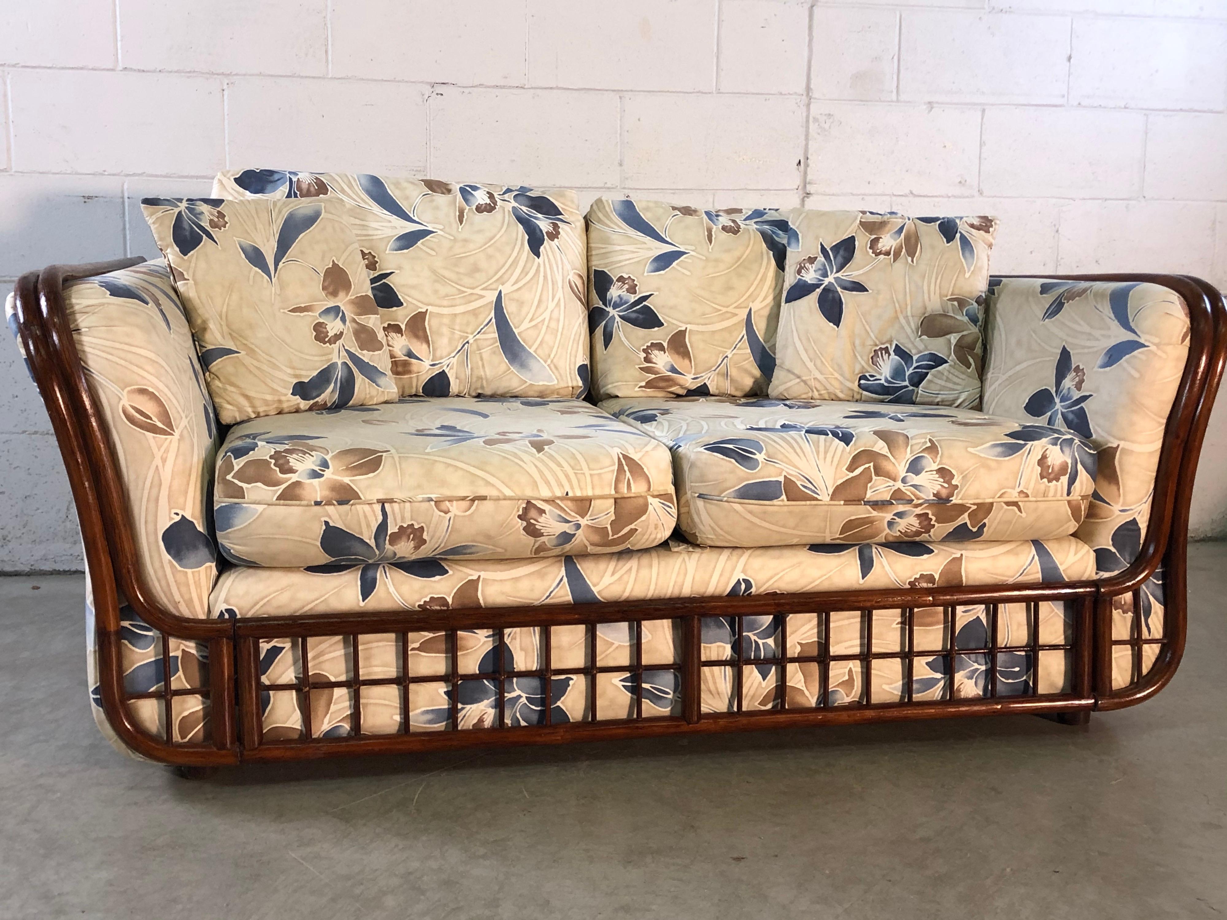 Vintage 1970s rattan and floral printed 2 seat sofa with curved arms. The sofa frame is a sturdy rattan and the sofa has the original floral print fabric that includes the back of the sofa. The fabric is in good condition with no ripes or stains. No