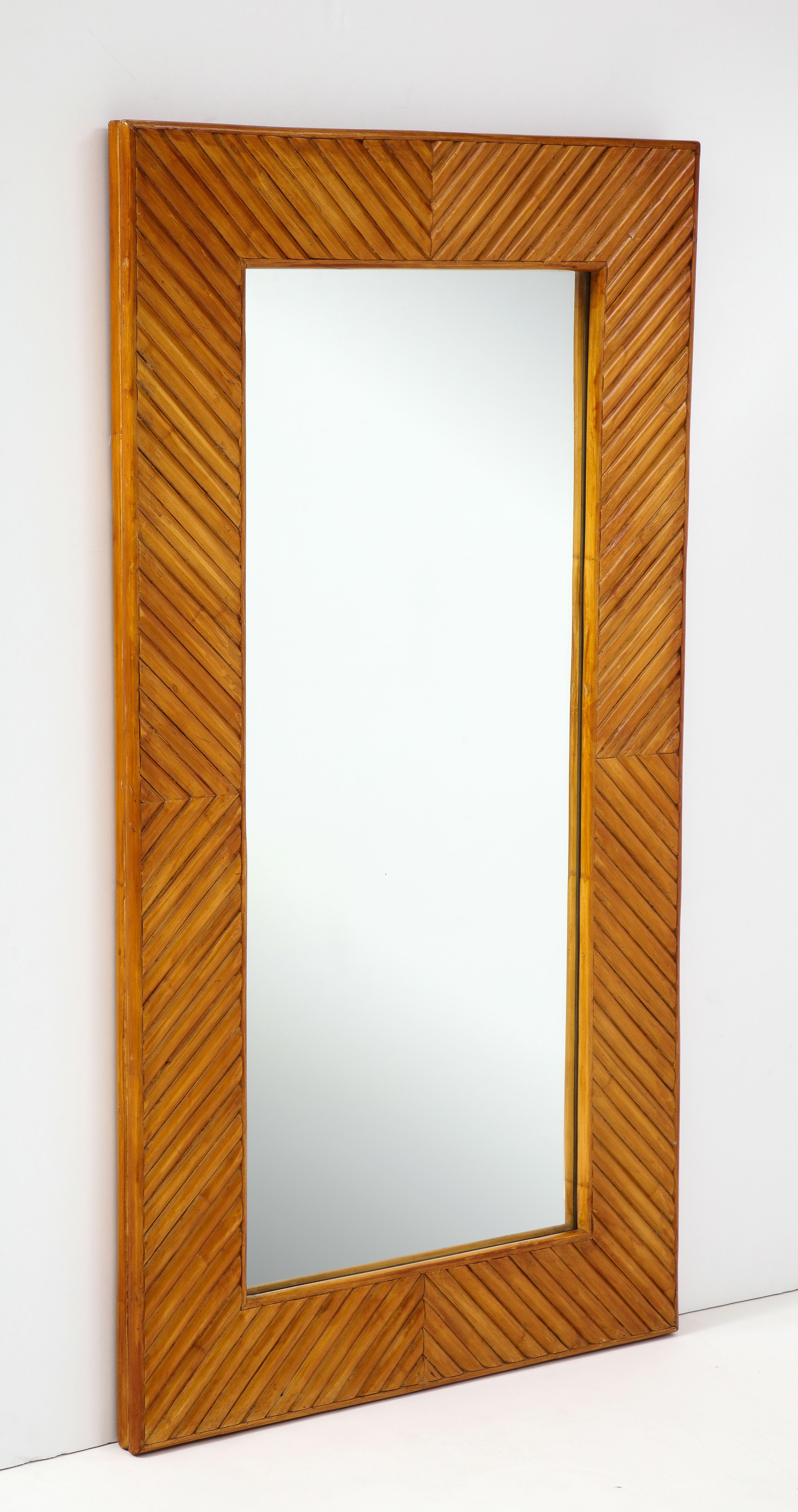 Vintage handcrafted rectangular bamboo mirror made with reed bamboo strips in a geometric design on the frame, Italy, 1970s. This stylish and chic mirror exudes 1970s glamour and is a unique handmade design. Restored with a new lacquer finish.