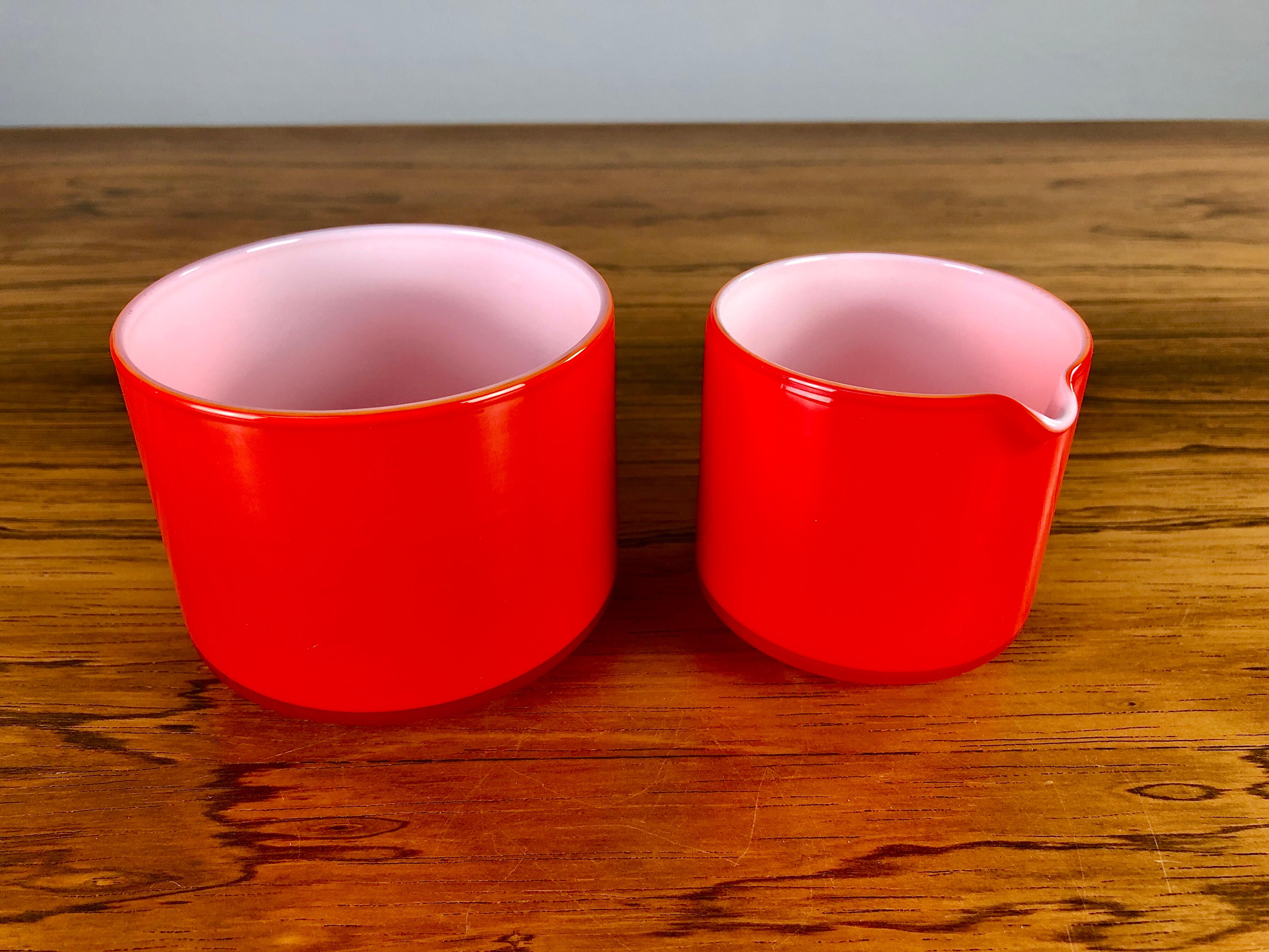Set of red creamer and sugar bowls in glass, designed by Michael Bang and produced by Holmegaard in the 1970s.

The well designed hand blown opal glass set with it´s 1970´s colors is in very good condition.

Michael Bang (1942-2013) was the son