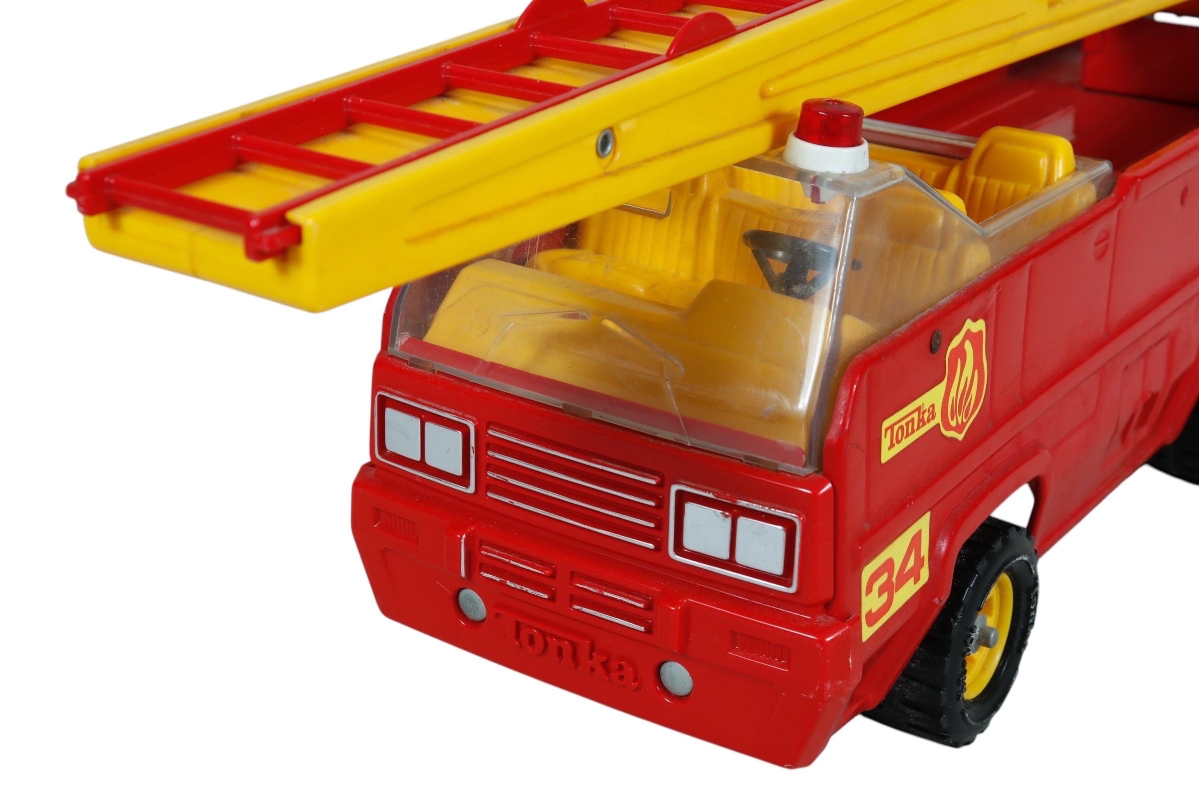 Un camión de bomberos rojo de los años 70 de Tonka, modelo XR-101. De cuerpo de acero prensado con plástico. En la parte superior hay una escalera que se extiende con un brazo de cuerda manual.