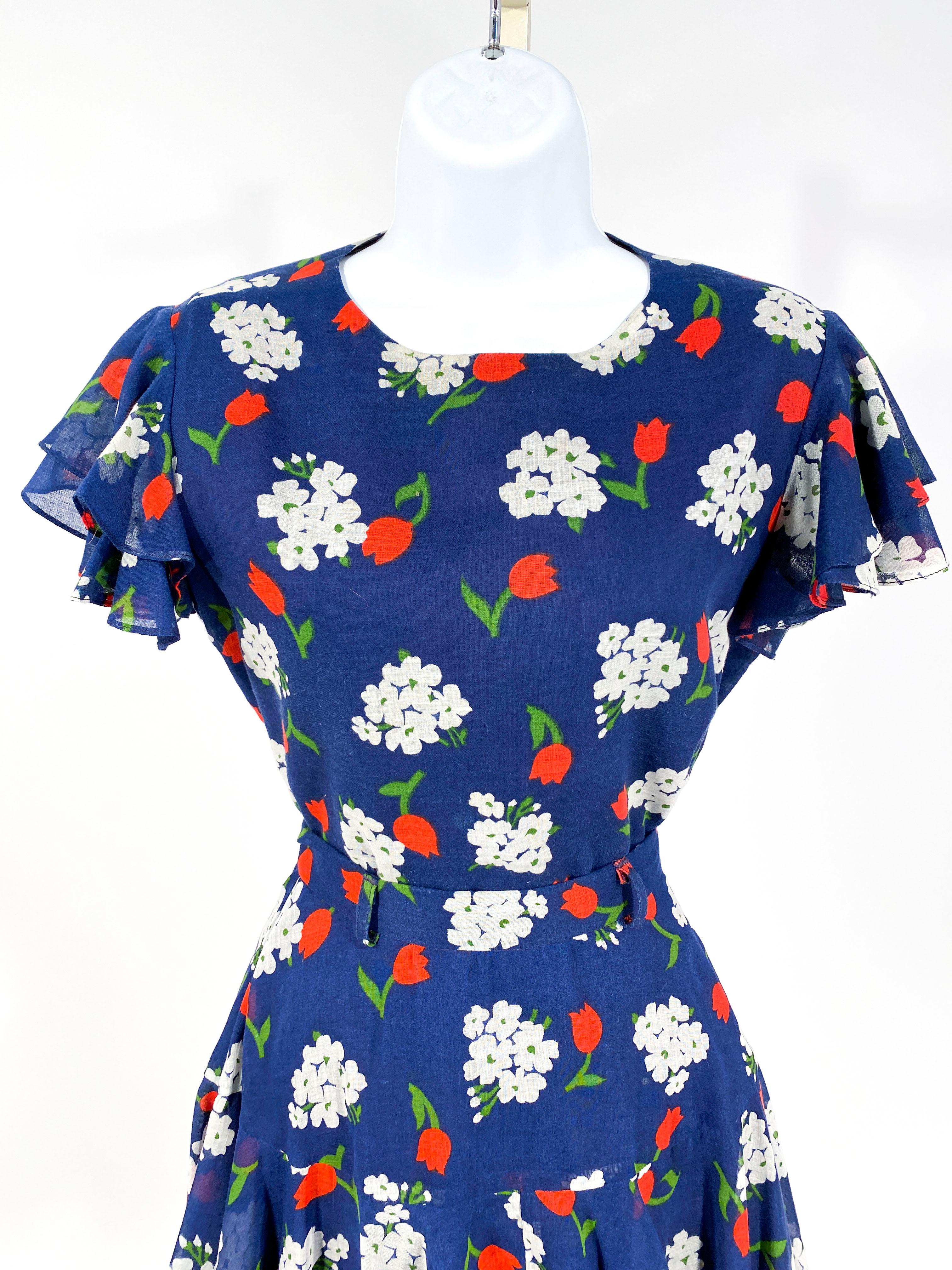 1970s two-piece (blouse and skirt) set featuring a red, white, and blue floral print. The shirt as layered ruffled short sleeves and is meant to be worn tucked into the skirt. The skirt has a fitted waist and begins to flare out below the hips. 