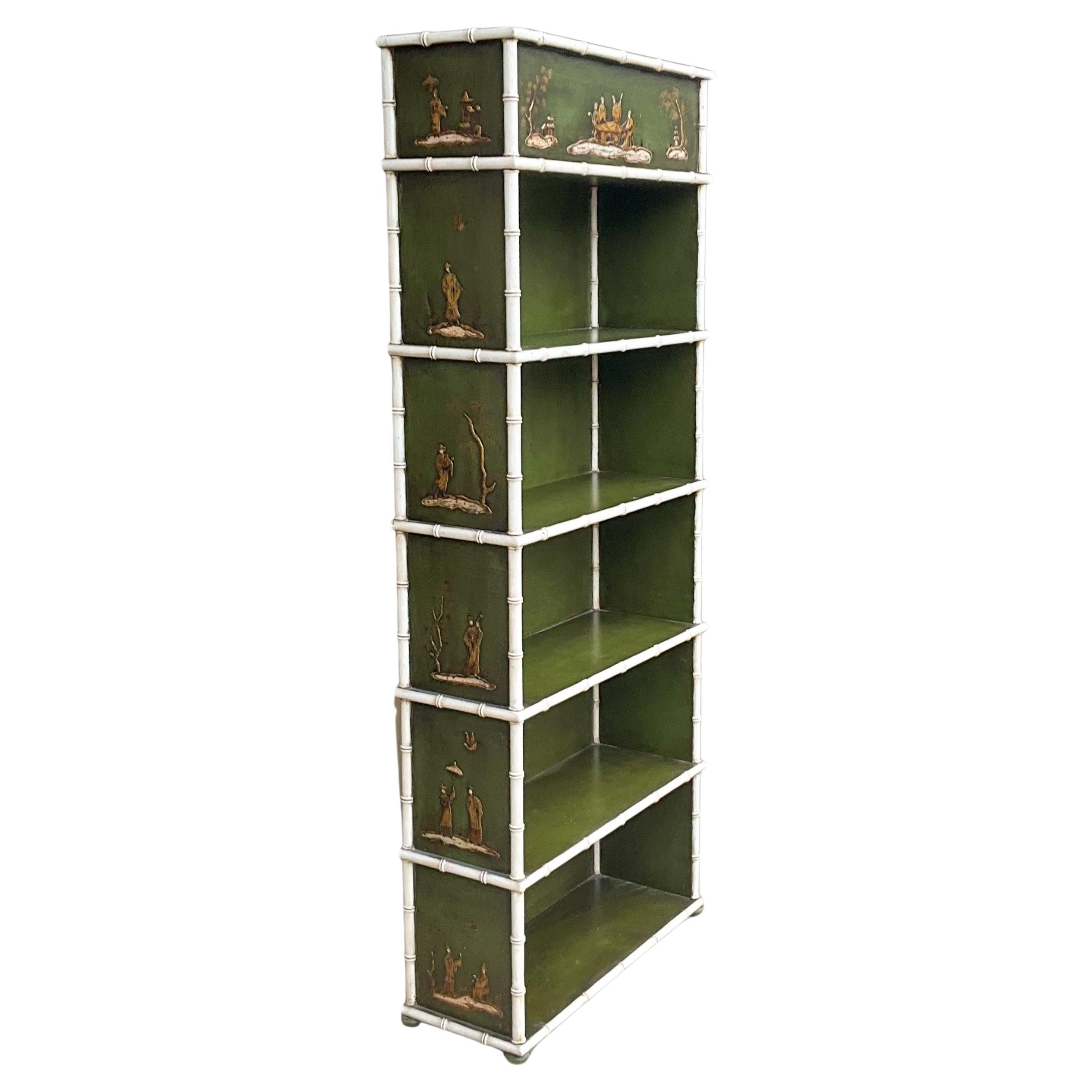 This is a late 20th century regency style chinoiserie and faux bamboo bookcase manufactured in Spain. It has a distressed white faux bamboo frame, and the body is a distressed green with hand painted gilt chinoiserie pastoral scenes. It is unmarked