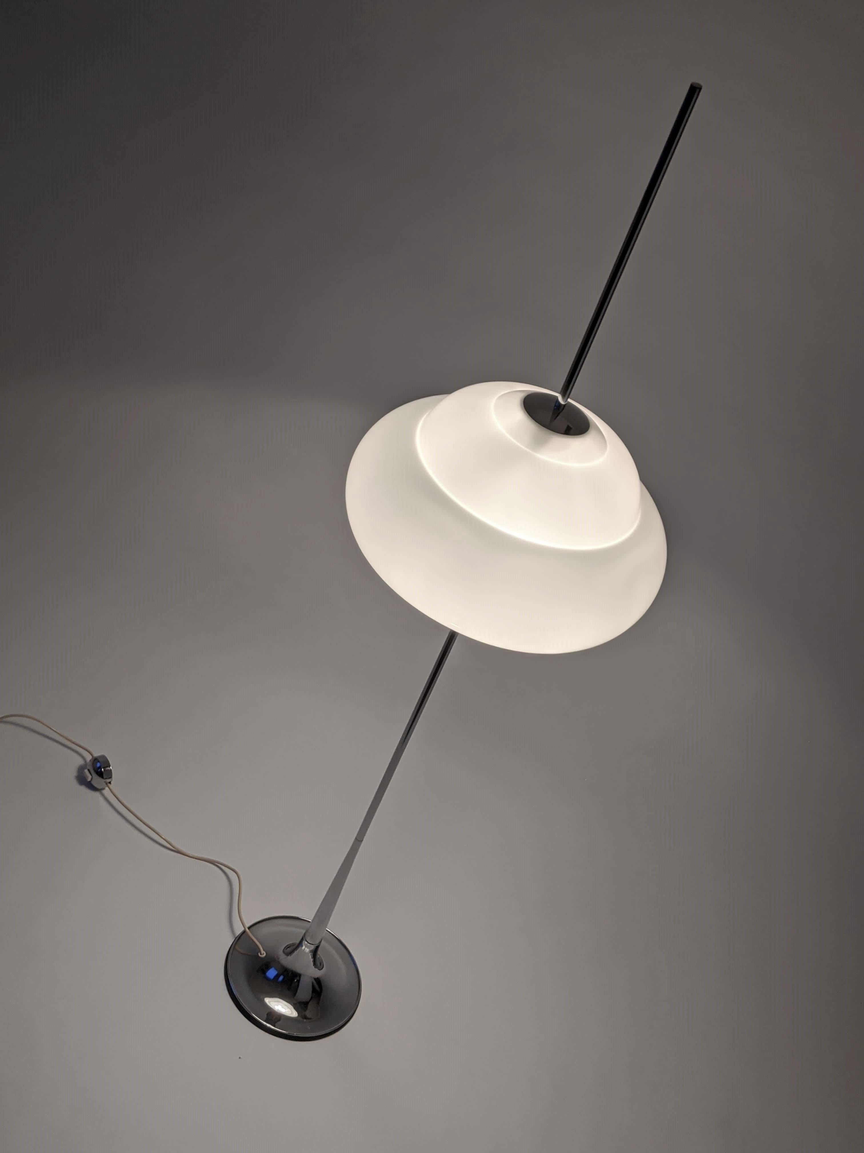 Reggiani Floor lamp with a shade having the apparence of being pierced trought by the chromed pole.

Provide a warm tone when lighted. 

Contain 3 E26 size socket rated at 60 watt each with individual chain pull switch. 

Foot switch on cord.