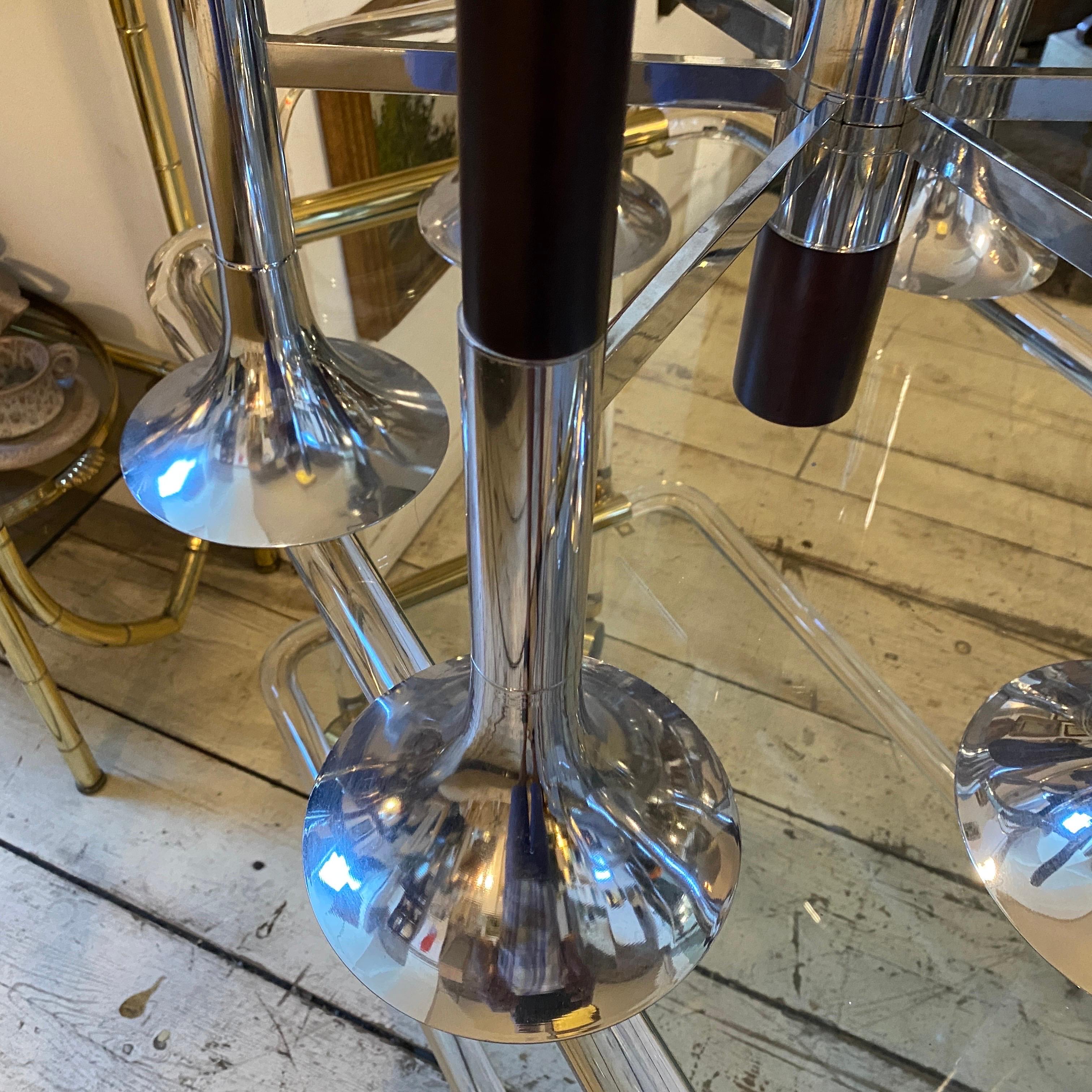 An amazing chromed steel and wood six lights chandelier designed and manufactured in Italy by Reggiani in the Seventies. It's in working order, it works both 110-240 volts and needs six regular e27 bulbs.
This Chandelier is a striking and iconic
