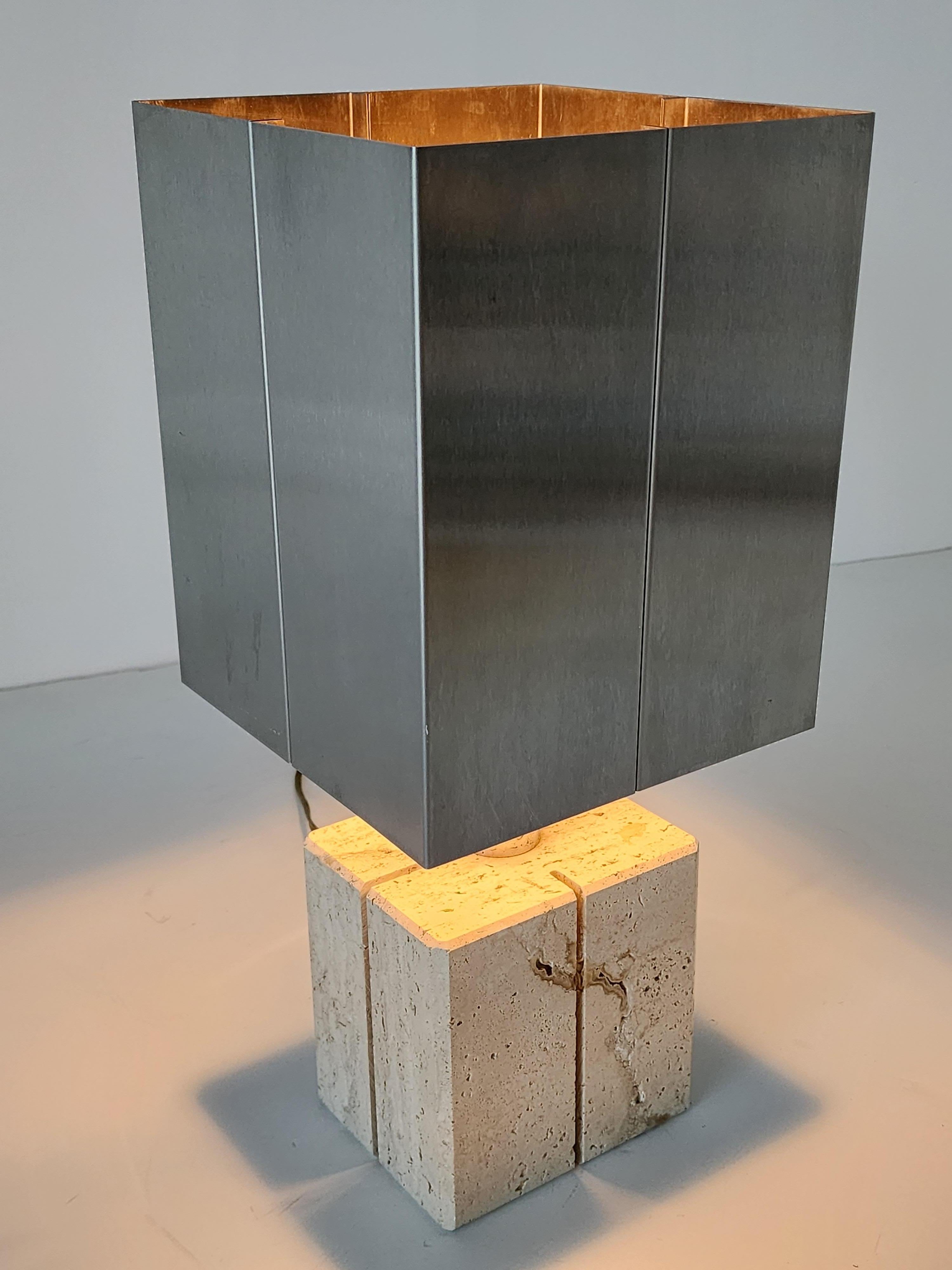 Lampe de table en travertin avec  Abat-jour en acier inoxydable de Reggiani Lighting , Italie .  

Contient une douille ordinaire de taille E26 d'une puissance de 60 watts. 

Interrupteur marche/arrêt sur la prise . 

La base en travertin mesure 6