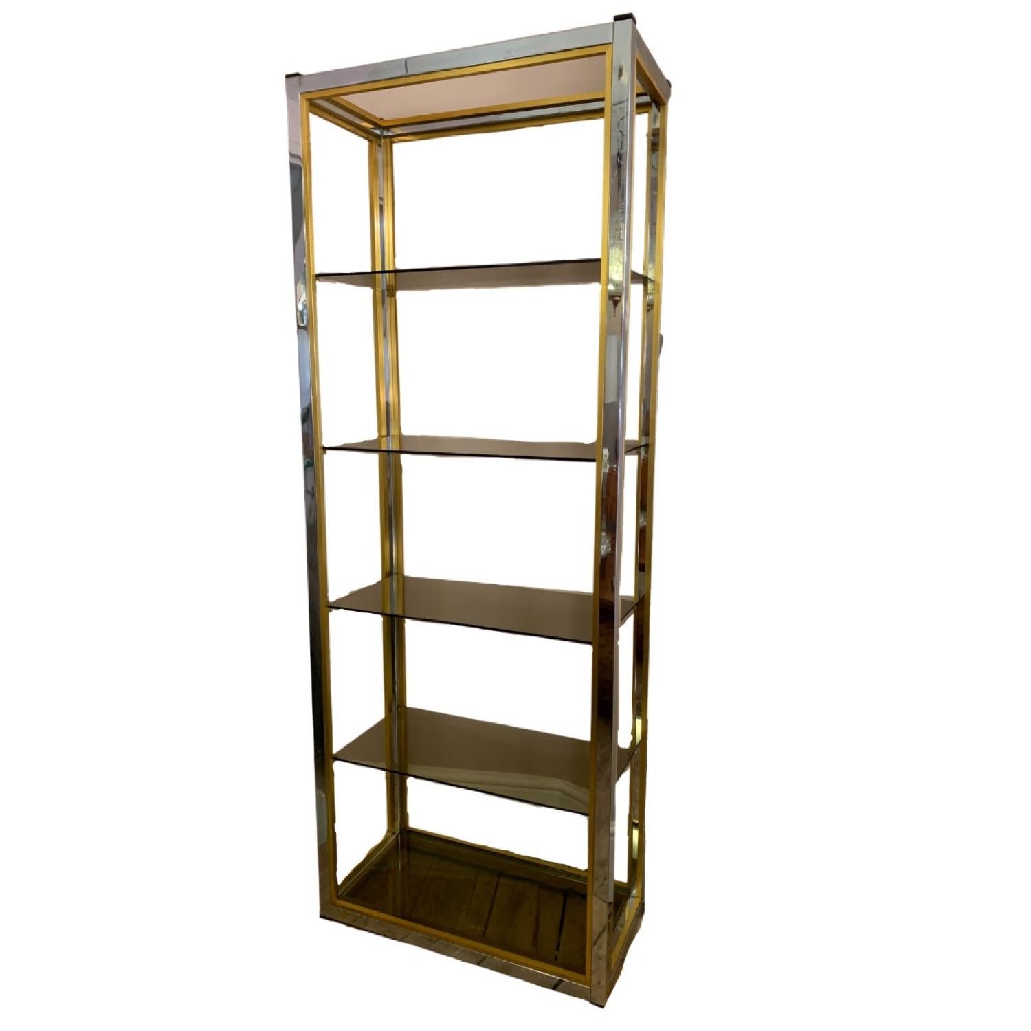 1970s brass and chrome tall and slim anodised chromed brass and chrome bookcase or etagere. Designed by Renato Zevi in a Hollywood Regency style. The original 5 smoked glass shelves which are all in very good condition with no chips or cracks. The