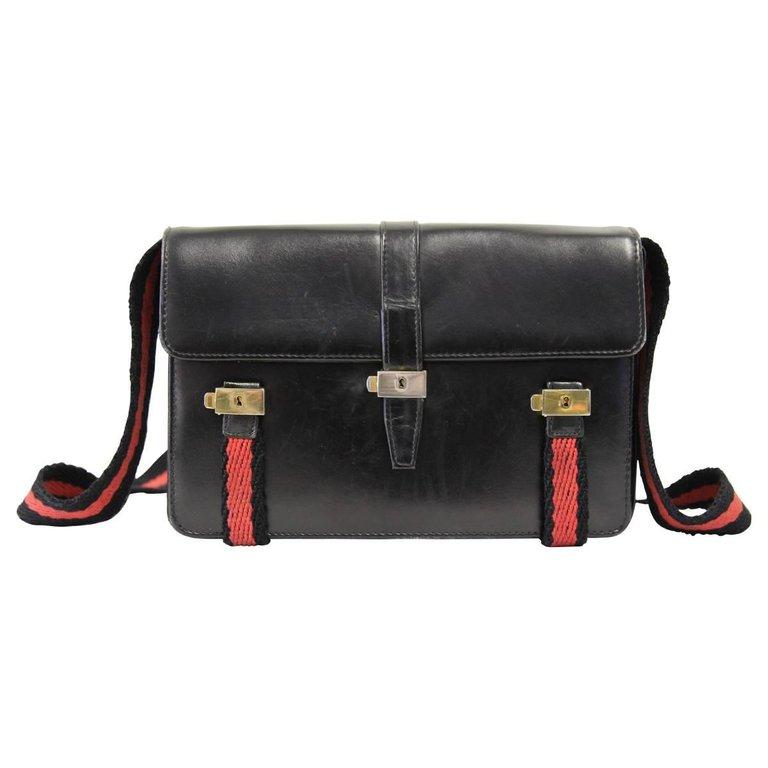 Roberta di Camerino black leather bag with red and black striped shoulder strap with gold-tone metal fancy press stud button front fastening, accordion details on the side, inner zip pocket.

The item is vintage, it shows light scratches on leather,