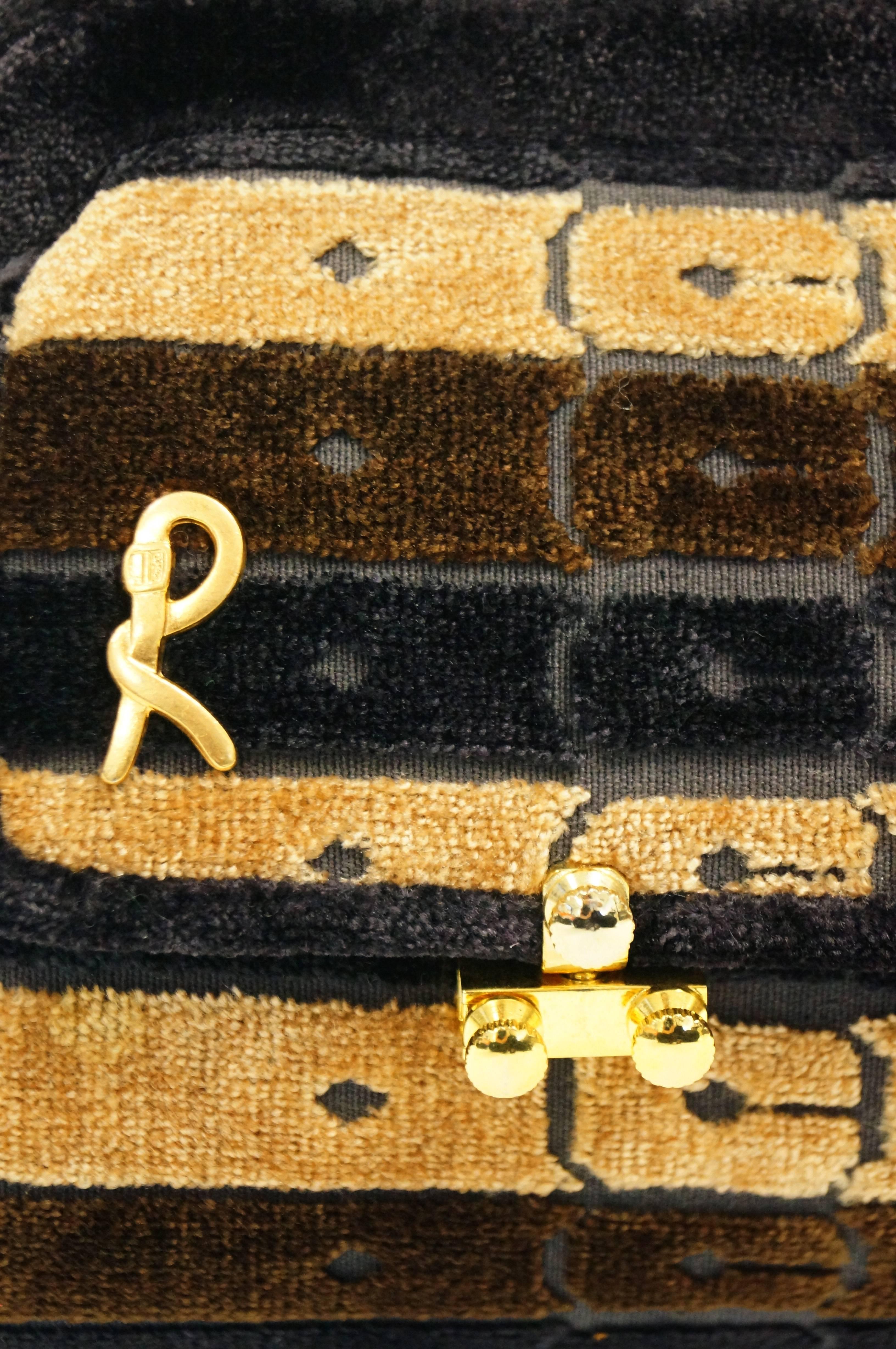 
This vintage purse by Roberta di Camerino is a wonderful, luxurious interpretation of the classic austere doctor bag! The bag is composed of plush velvet cut in a distinct belt and buckle pattern of gold, brown, and black stripes. The famous