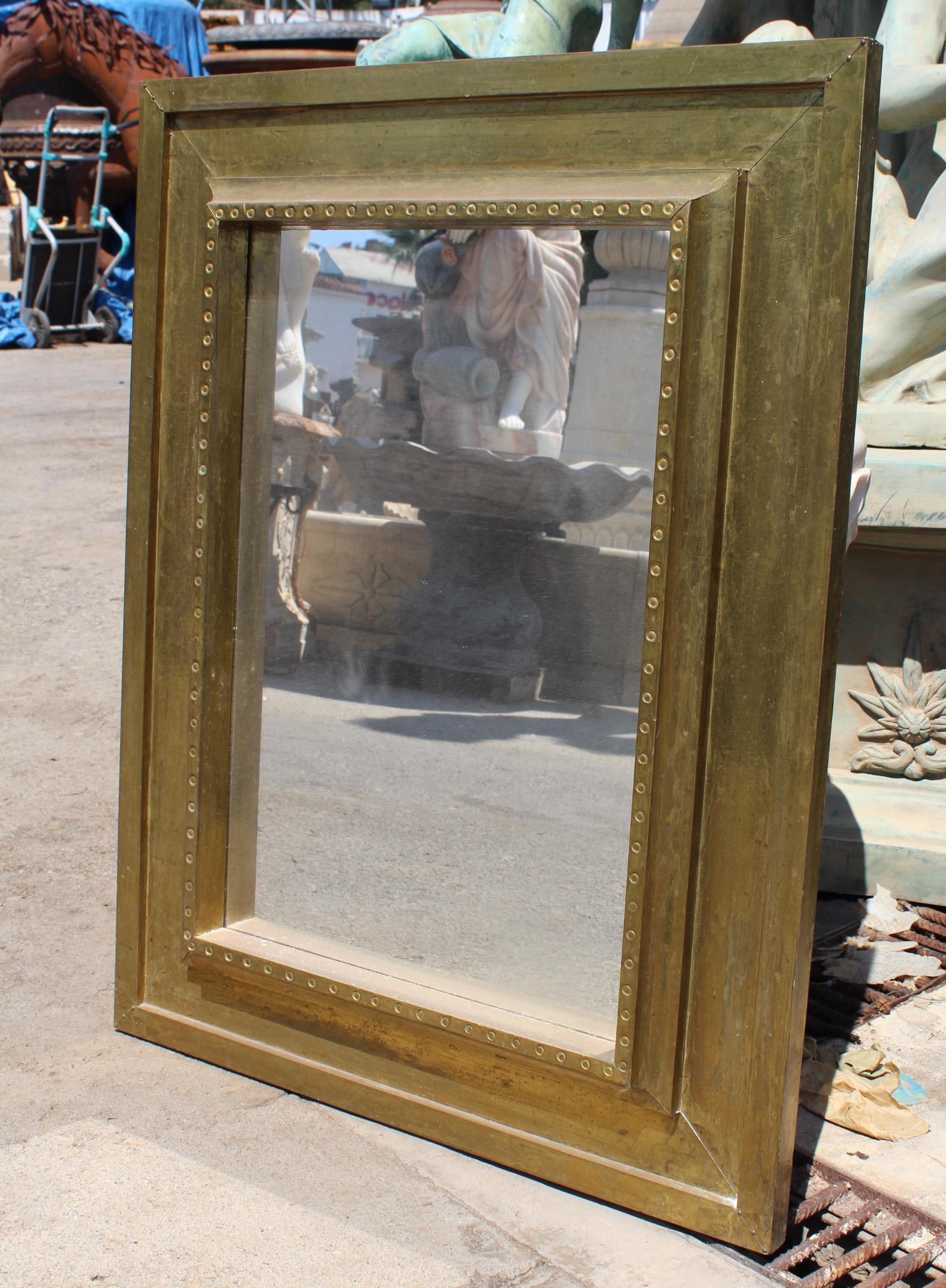 1970s handcrafted gilded brass panels stamped over a wooden frame mirror by Rodolfo Dubarry's workshop in Marbella. 

50 years ago, Argentinian furniture designer Rodolfo Dubarry set up a workshop in Spain and popularised the use of gilded brass