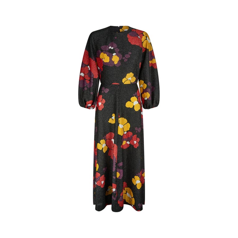 This is such a striking 1970s floral lame maxi dress. The base colour is black with silver flecks acting as a backdrop for giant blowsy flowers in red, yellow and purple tones with white centres. The lame of the flower motifs has a more bronze &