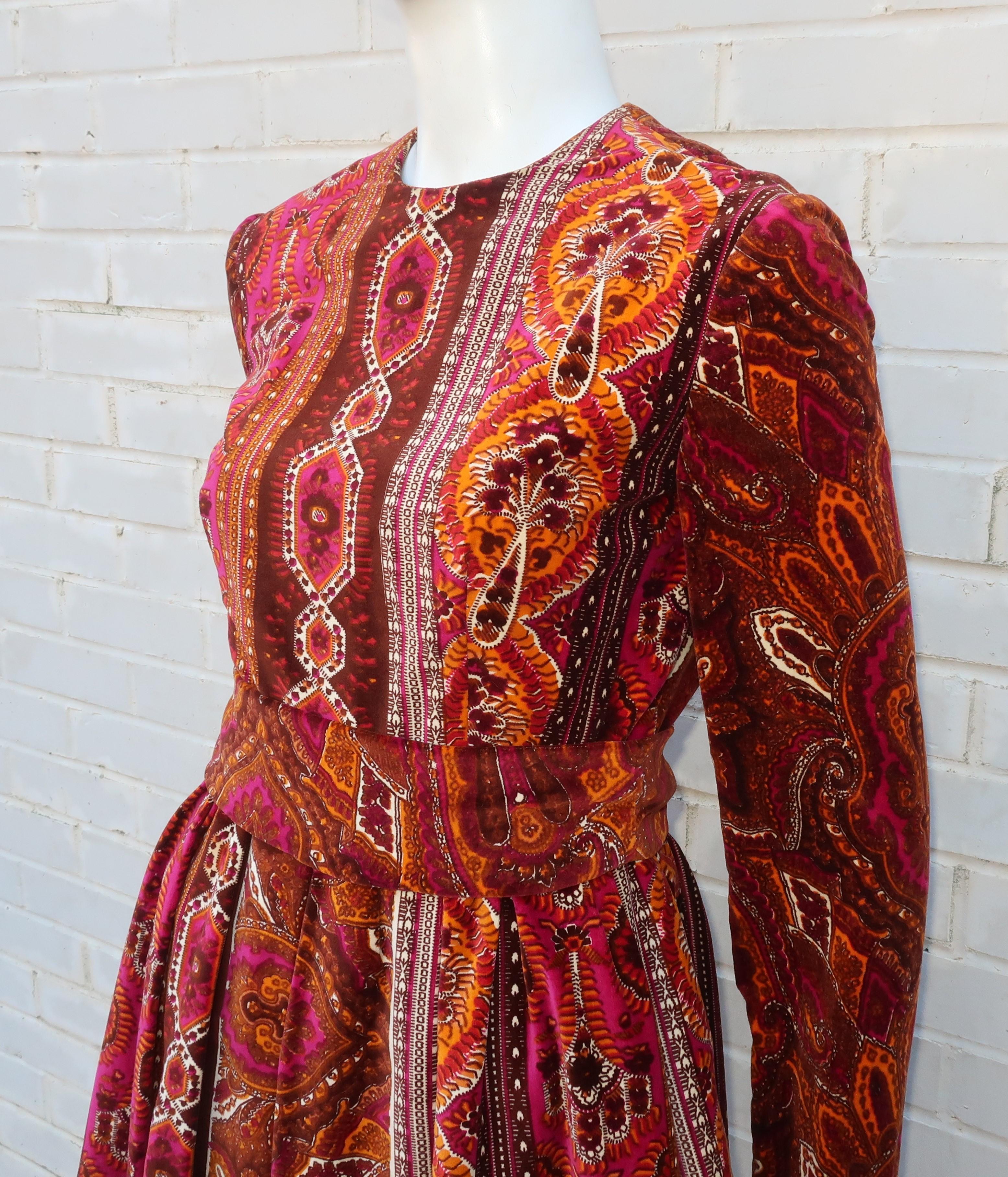 Enter the rich world of an exotic and colorful paisley style print with this 1970's Rodrigues pleated dress.  The lush feel of the velveteen fabric combined with the vibrant color combination of browns, orange, fuchsia pink and winter white lends