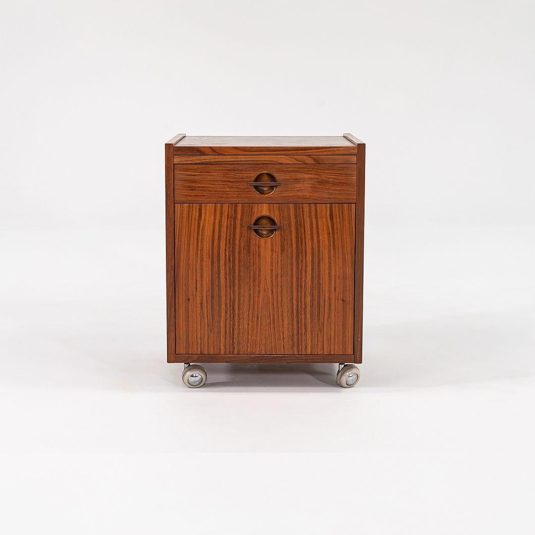 This is a Rolling Teak Bedside Table, designed by W&B Mobler and produced by Axelsens Mobelfabrik. This piece comes from the 1970s and was produced in Denmark. The bedside table is comprised of teak and sits on castors, it also features a small