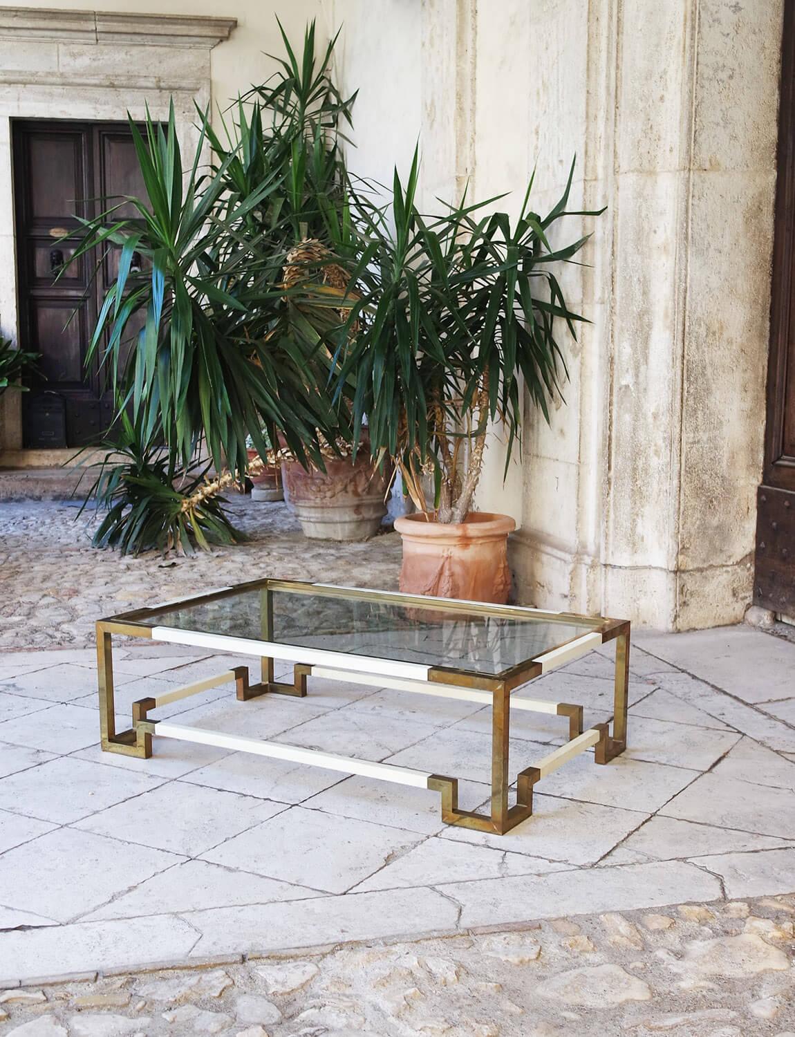 Romeo Rega cream resin and brass coffee table. This 1970s piece has a glass top and interestingly designed geometric legs. Please note, this is a vintage piece and there is a patina on the brass and light scratches and scuffs on the cream resin.  It