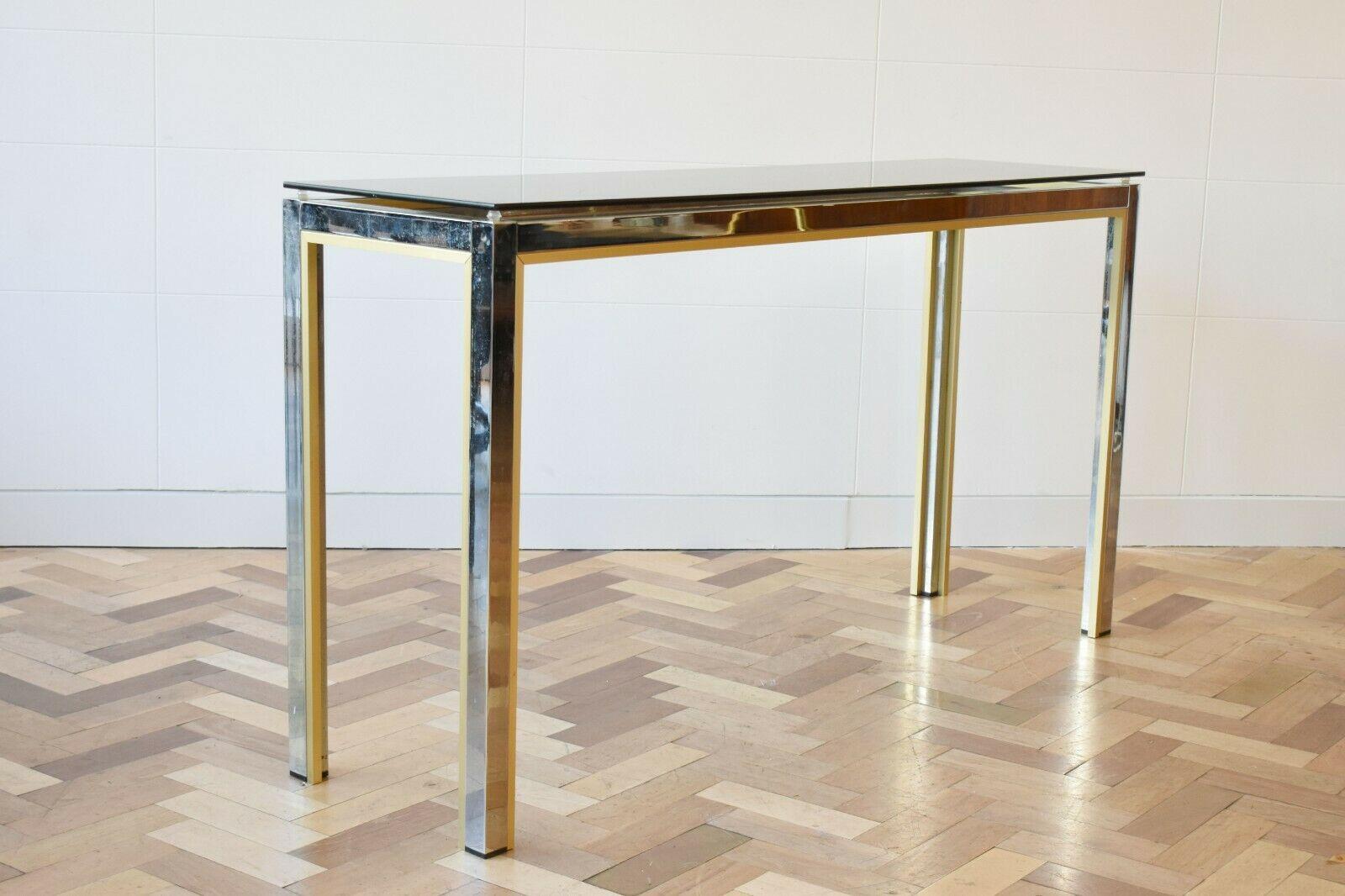 Mid-century 1970s Italian chrome and brass console table by Romeo Rega, with glass top.

A beautiful and sleek design, remnant of the Hollywood Regency period. 

About the designer: 

Born in 1904, Italian designer Romeo Rega is one of several