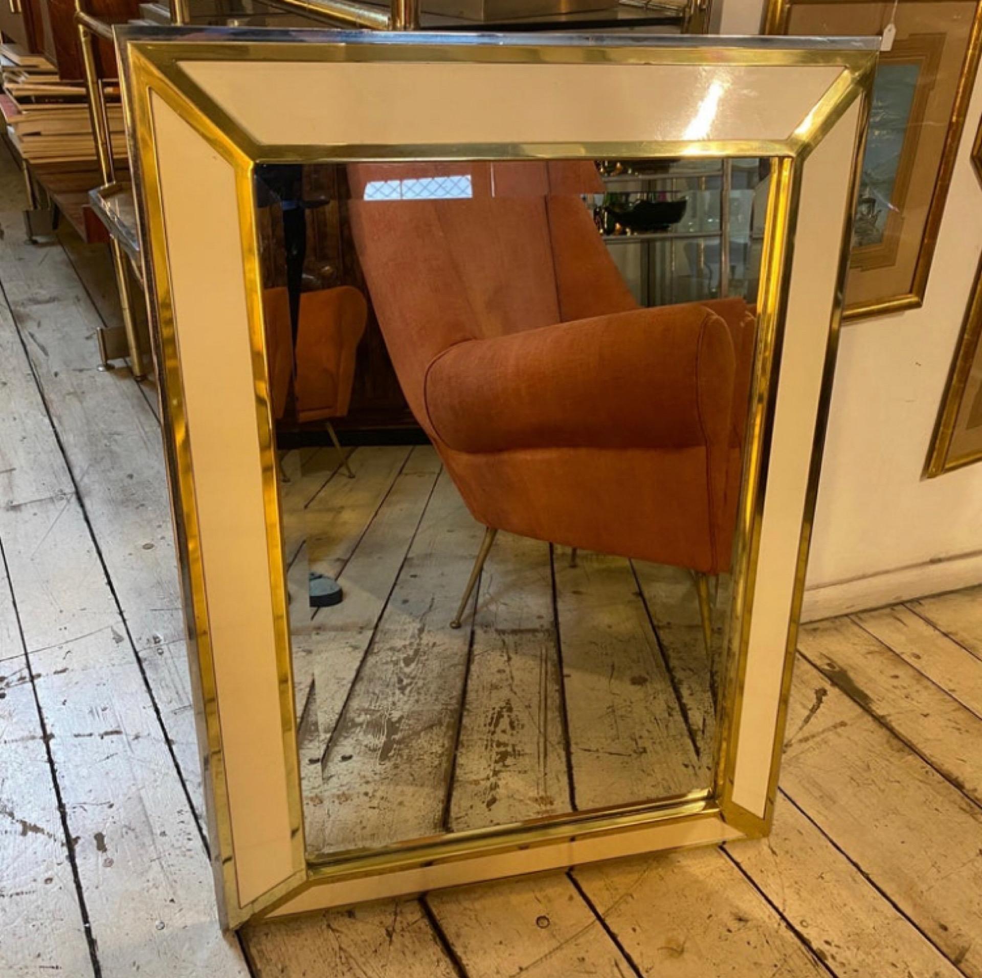 An amazing huge wall mirror made in Italy in the Seventies, chromed metal and brass parts are in perfect conditions like the mirror glass, the white panels gives it an elegant vintage look. The shape and the materials are in the style of the famous