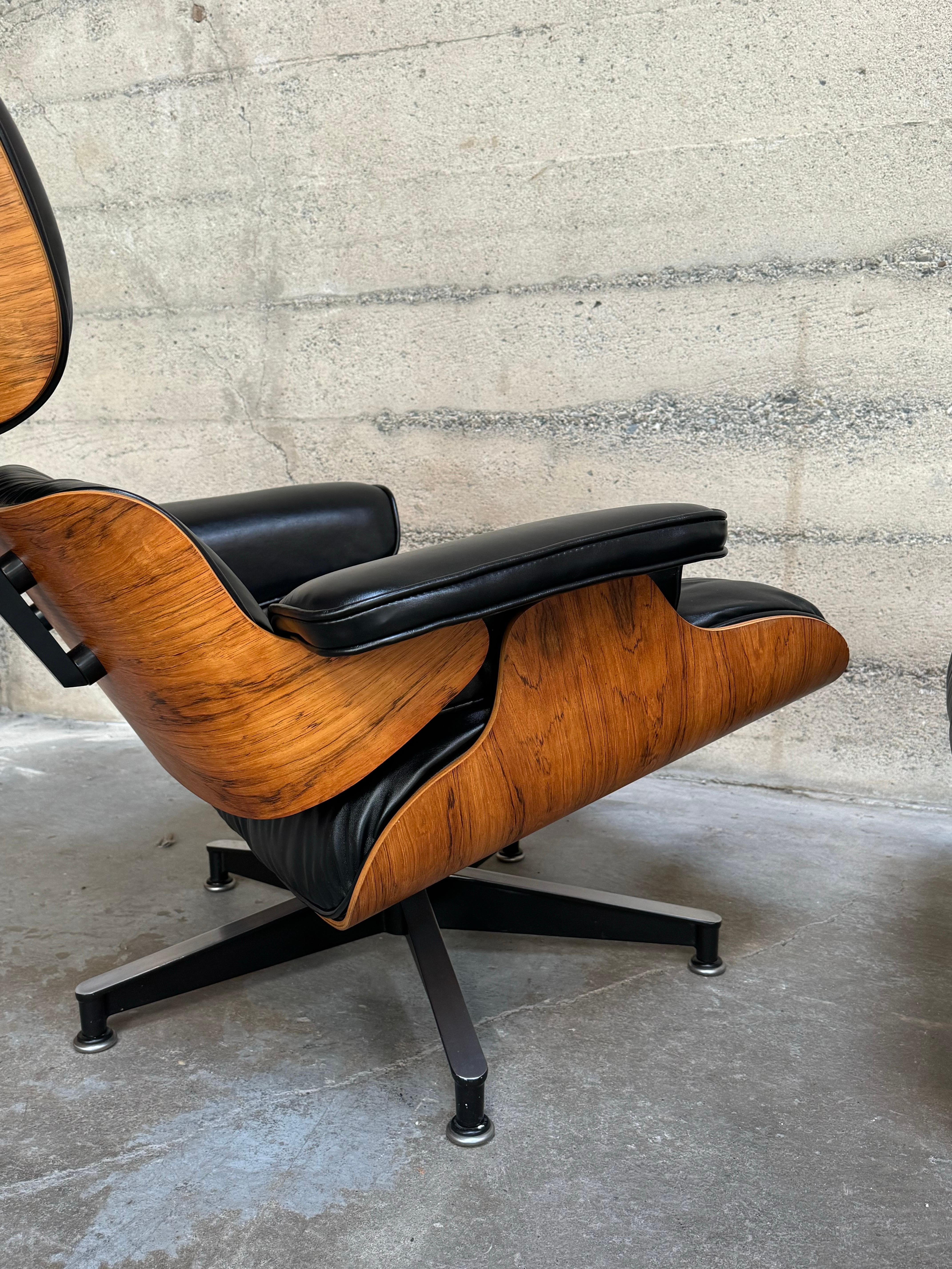 Eames lounge and ottoman with rosewood shells and upholstered in premium black leather from Austria. The rosewood is a lighter shade in the blonde range with figurative black graining to the wood. The chair has undergone a complete restoration with