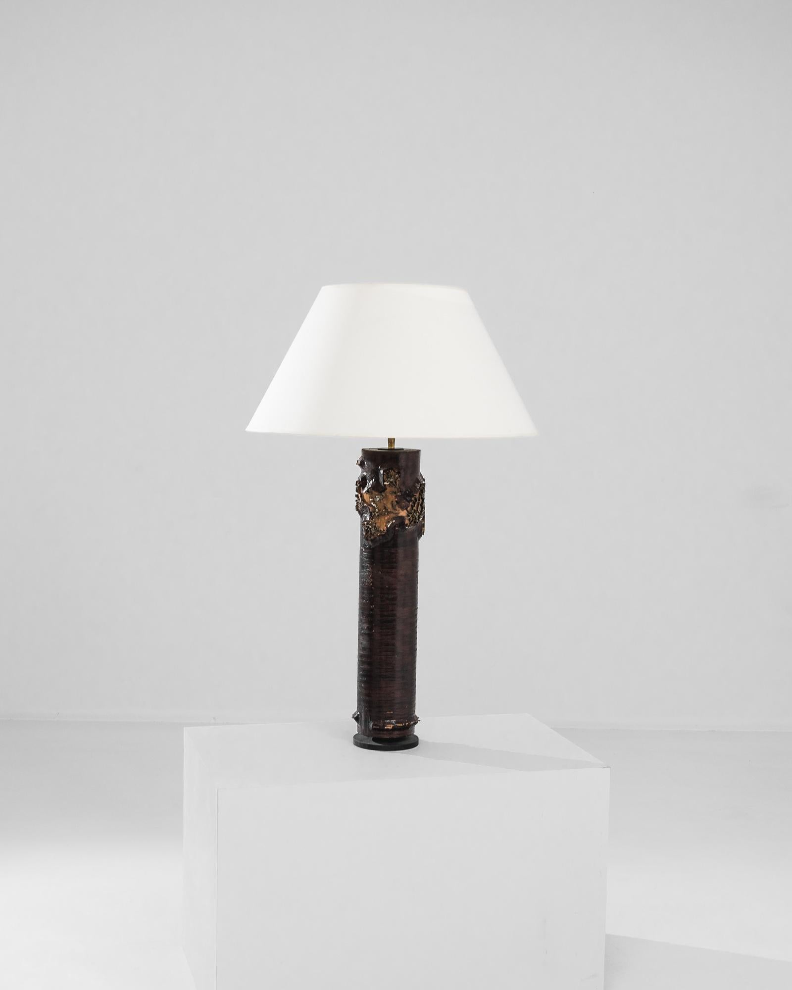 Une lampe de table en bois de France, produite vers 1970. Une colonne sculptée, un cylindre gravé : un ancien rouleau d'impression de papier peint en héliogravure devient une charmante lampe de table vintage, s'élevant à plus d'un mètre. Recouverte