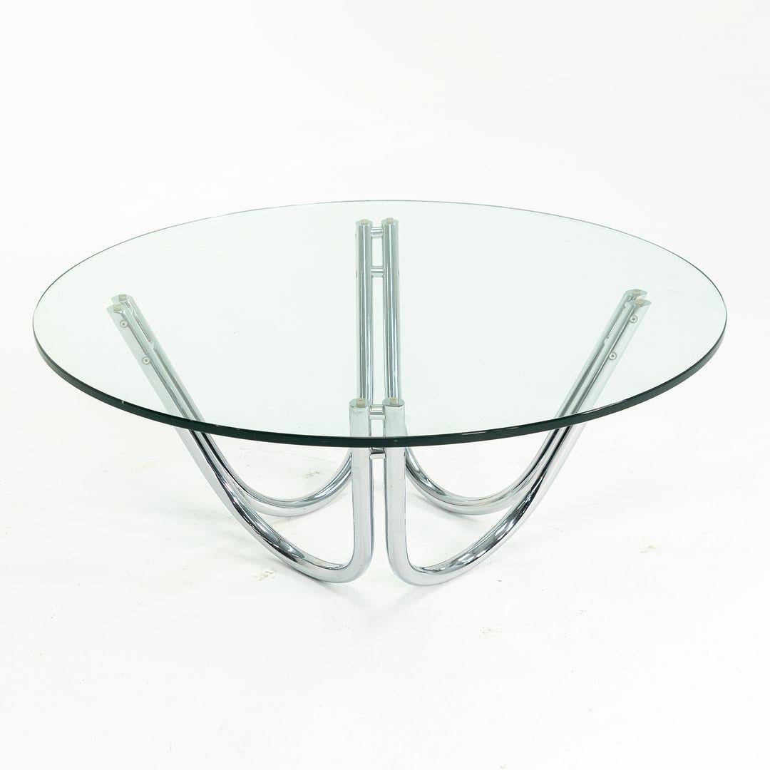 This is a sculptural coffee table, manufactured circa 1970s. It features a heavy chromed-steel base and retains its original glass top. The upswept U-shaped base can be inverted to create a different look if so desired. The piece appears very