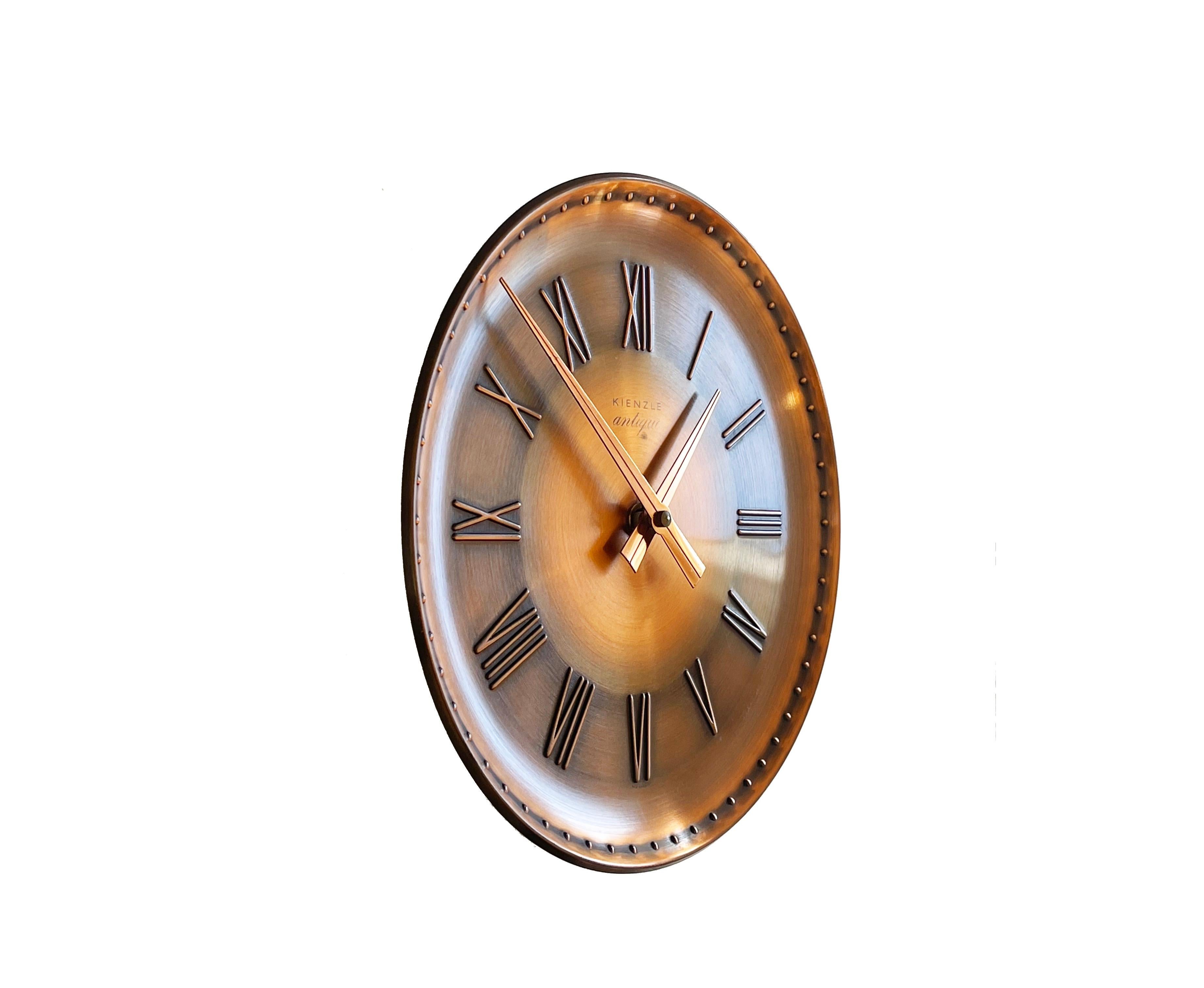 Horloge originale des années 1970 en cuivre pur, avec des chiffres romains en relief, fabriquée par Kienzle dans la série ''Antique''. 
Horloge à quartz de Hechinger, Allemagne.
Merveilleux design typique des années 70. 
Légèrement incurvé à