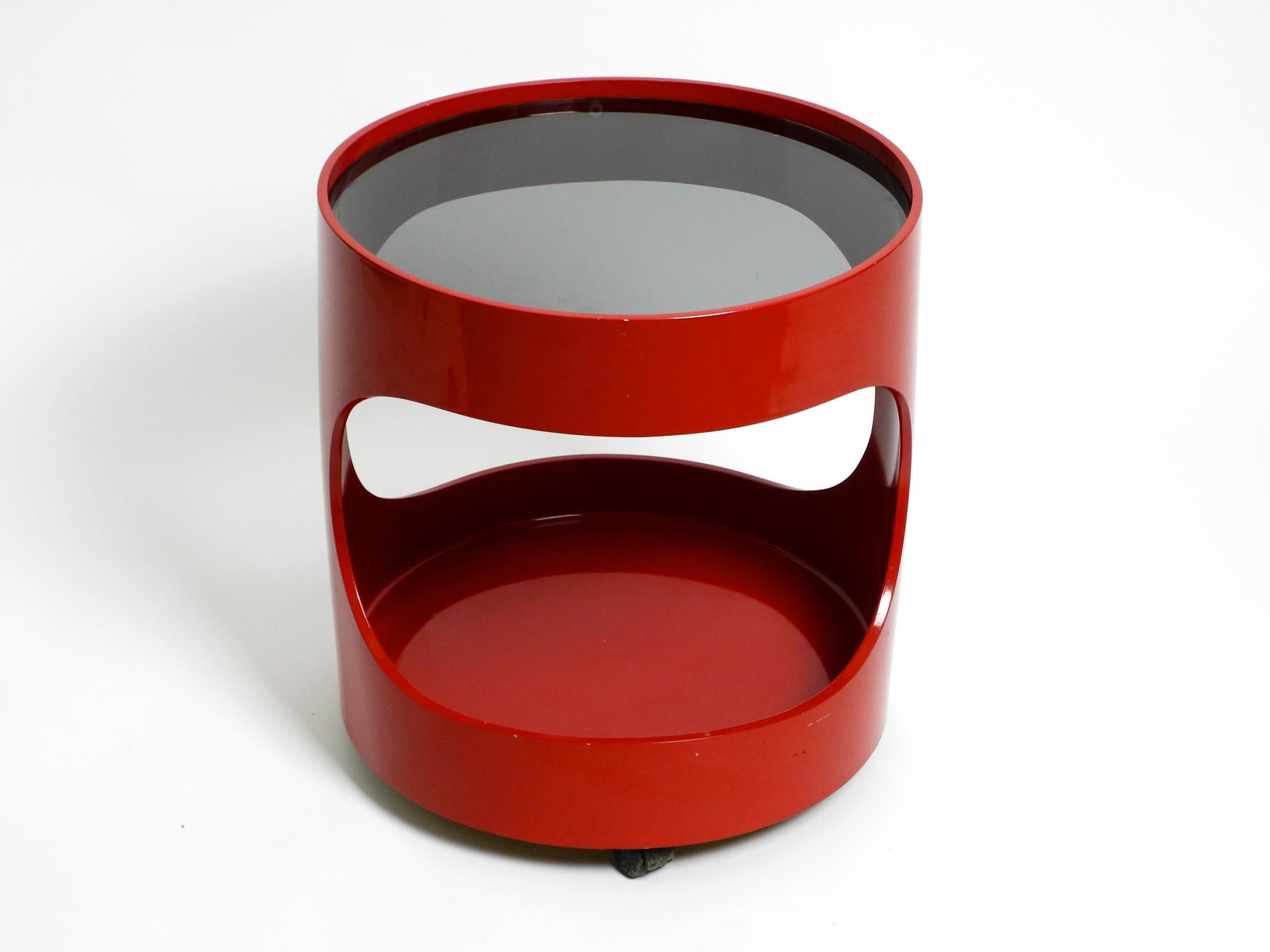 Beautiful rare original 1970s red round side table from Opal. Model Luna.
Very beautiful space age design with a real smoked glass plate. Table frame is made of red plastic.
With 4 wheels on the bottom. Moves very smoothly and quietly in all