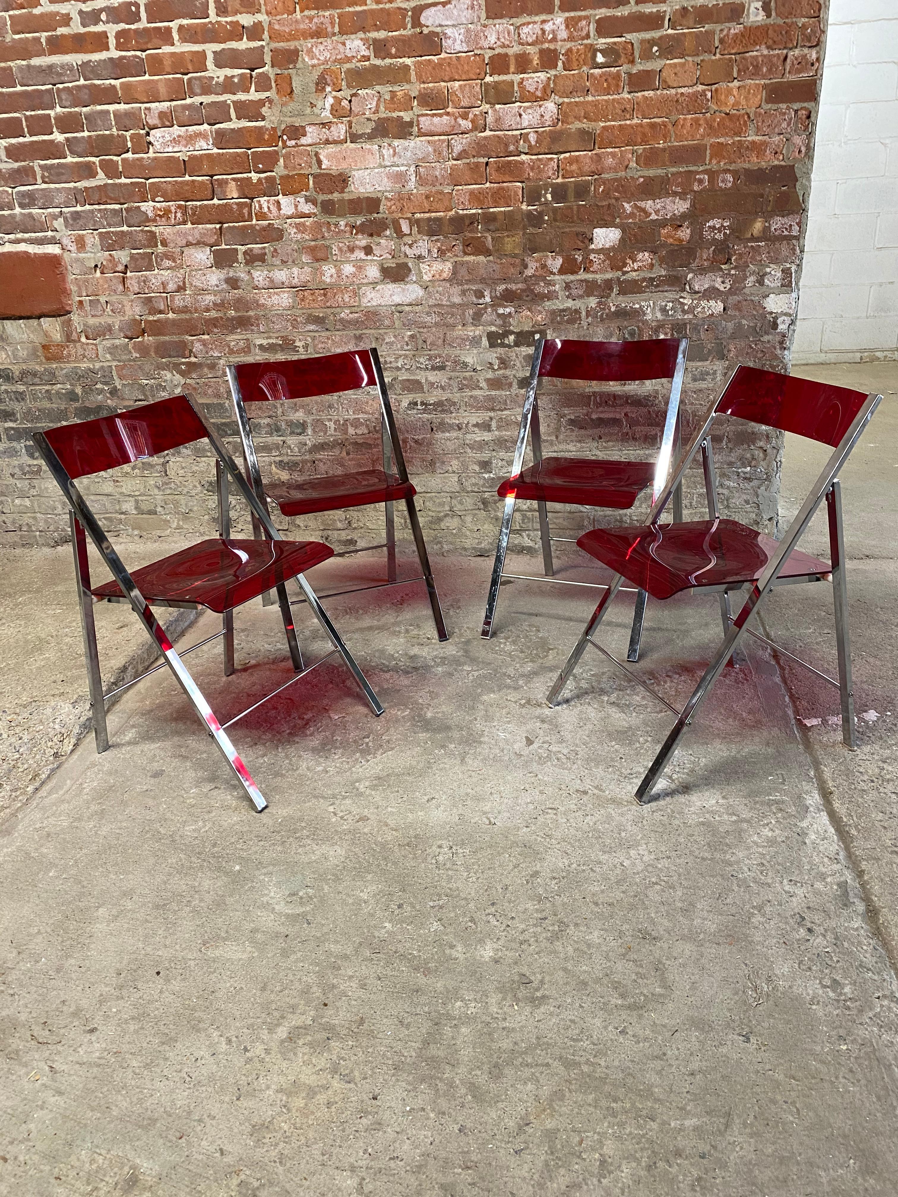 Set of four red acrylic and chrome folding chairs. Great for the small apartment or just for space saving needs. Fun and vibrant shaped red acrylic seats and back rests with flat bar chrome frames. Circa 1970-80. Good overall condition. All