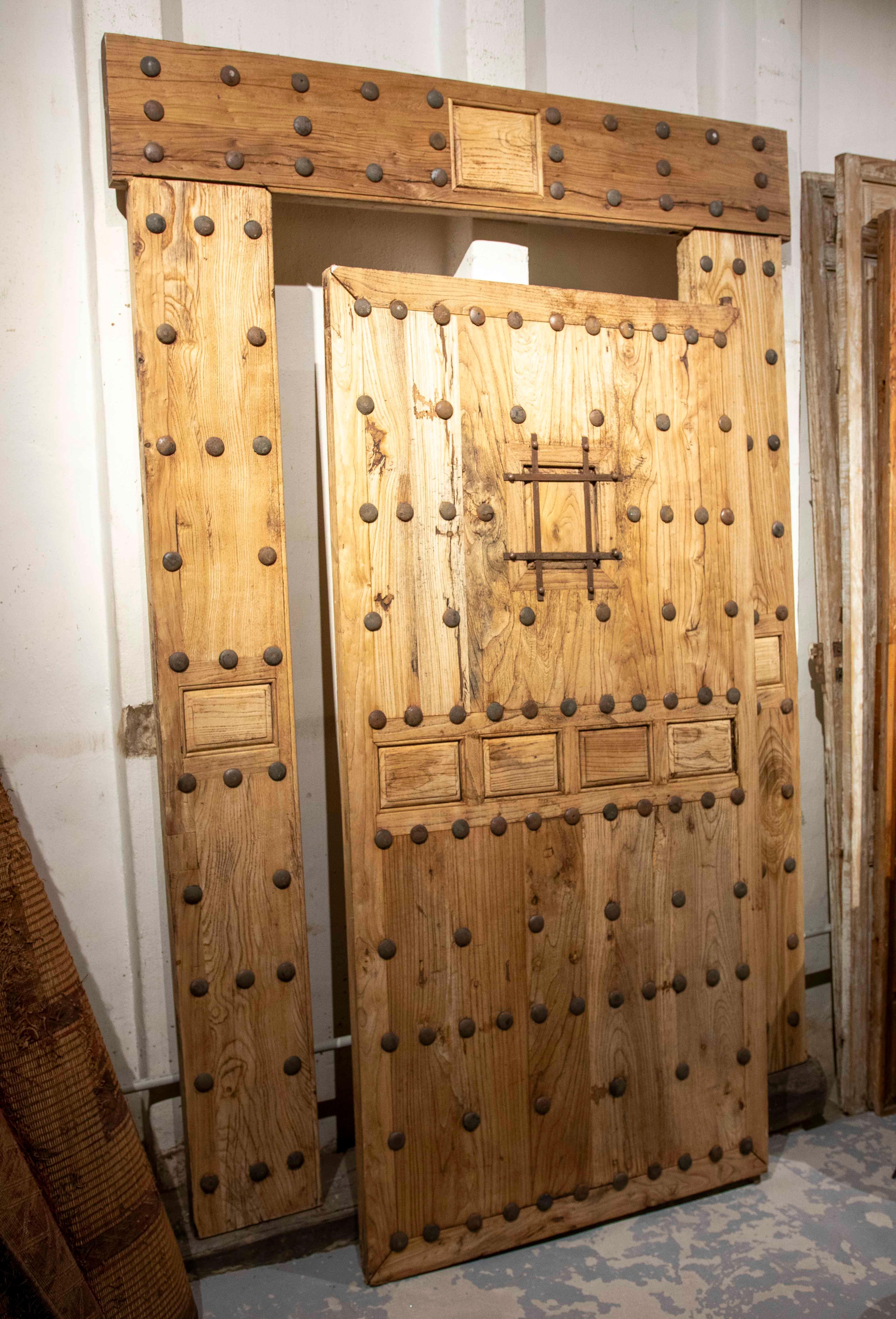 Stupendo cancello spagnolo antico in legno massiccio dal design robusto e tradizionale. La struttura comprende una cornice e un'anta decorata con grandi chiodi metallici disposti simmetricamente che aggiungono carattere e autenticità. Al centro