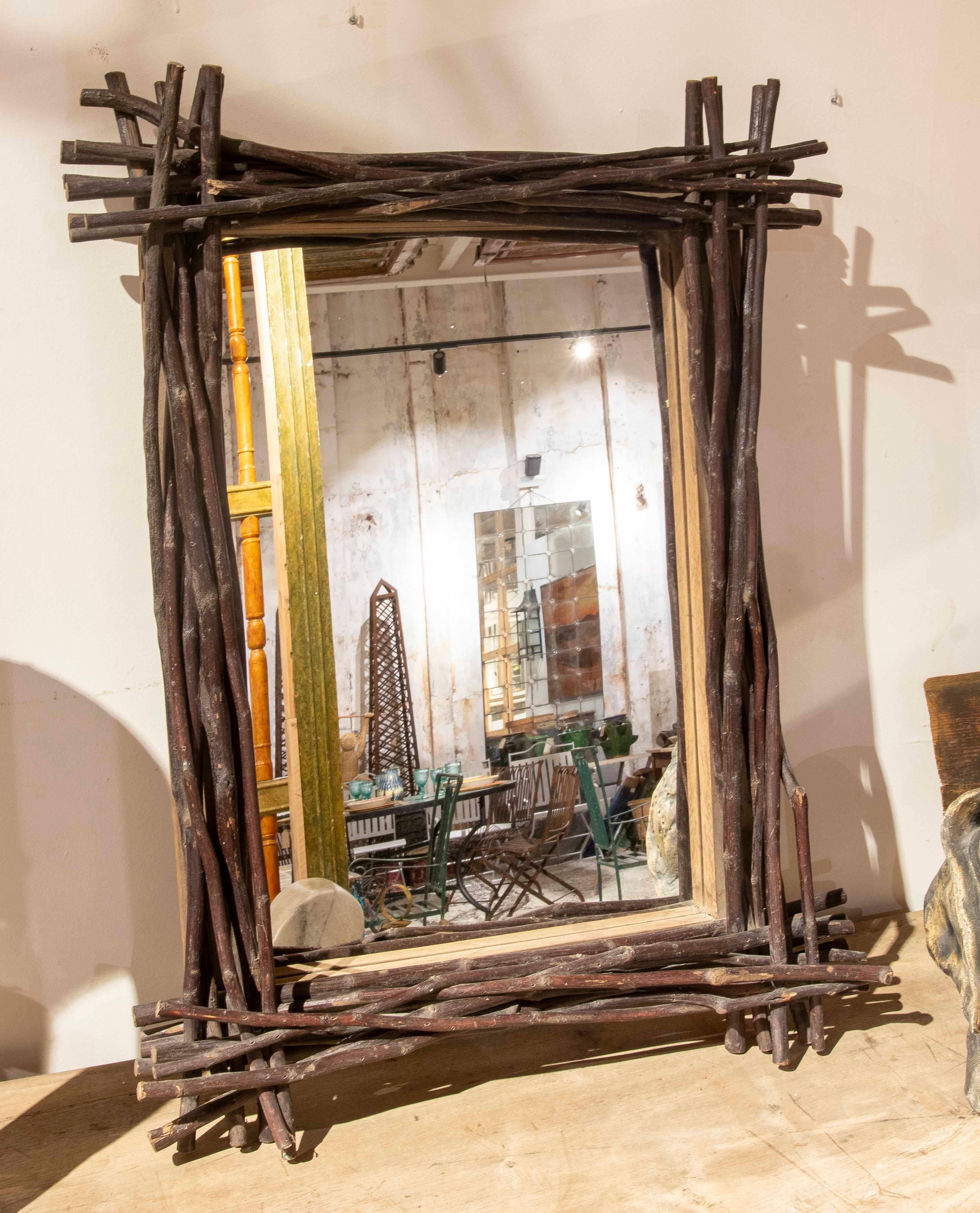 A unique decorative mirror with a handcrafted frame crafted from intertwined natural wood branches, giving it a rustic, organic, and sculptural character. The irregular arrangement of the branches creates a dynamic and unique effect, evoking a